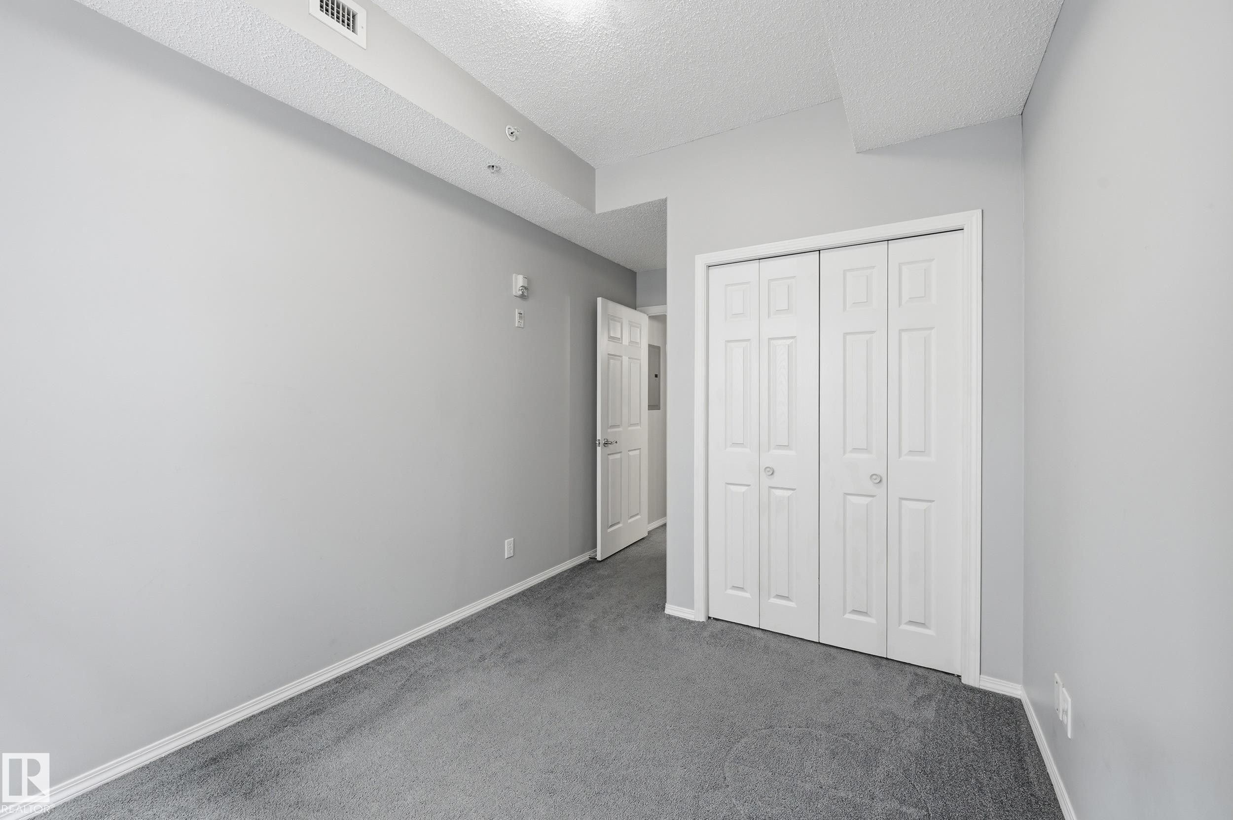 Room featuring light gray walls and gray carpeting - 203 11103 84 Avenue, Edmonton, AB