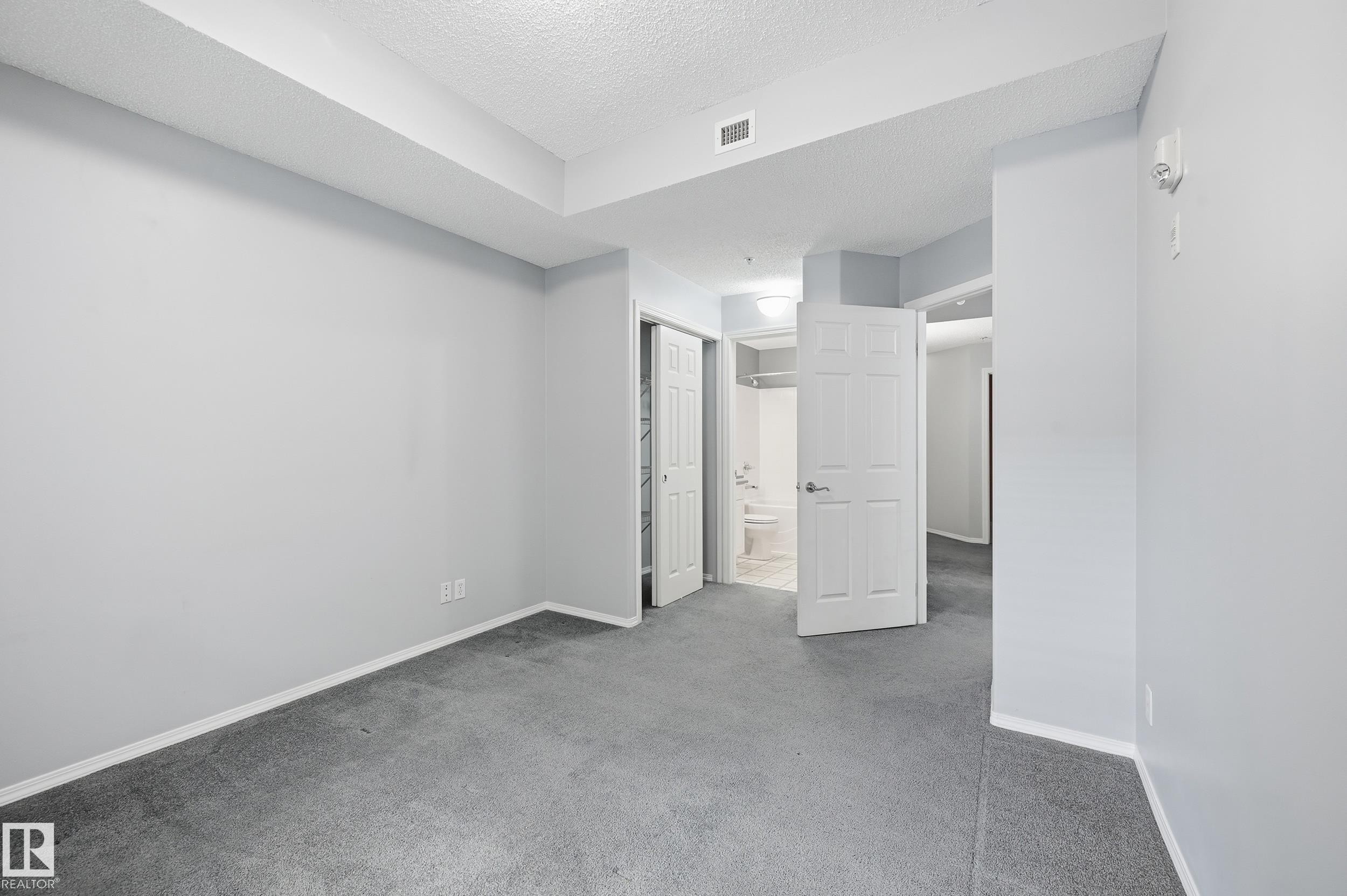 Spacious room with light gray walls, gray carpeting, and white trim - 203 11103 84 Avenue, Edmonton, AB