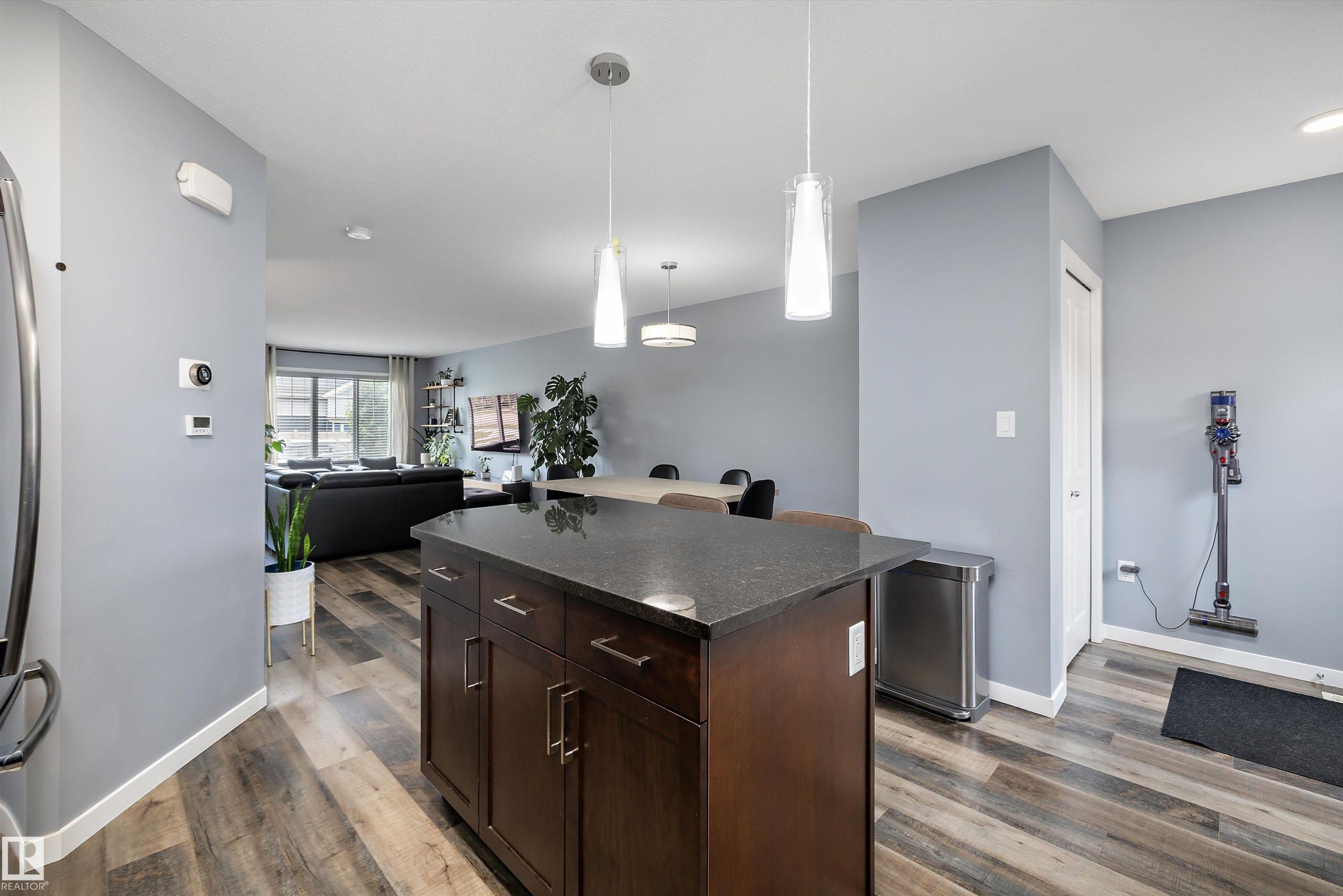 Kitchen island featuring a dark wood-finish base with cabinet storage and a dark countertop - 2833 Chokecherry Place, Edmonton, AB