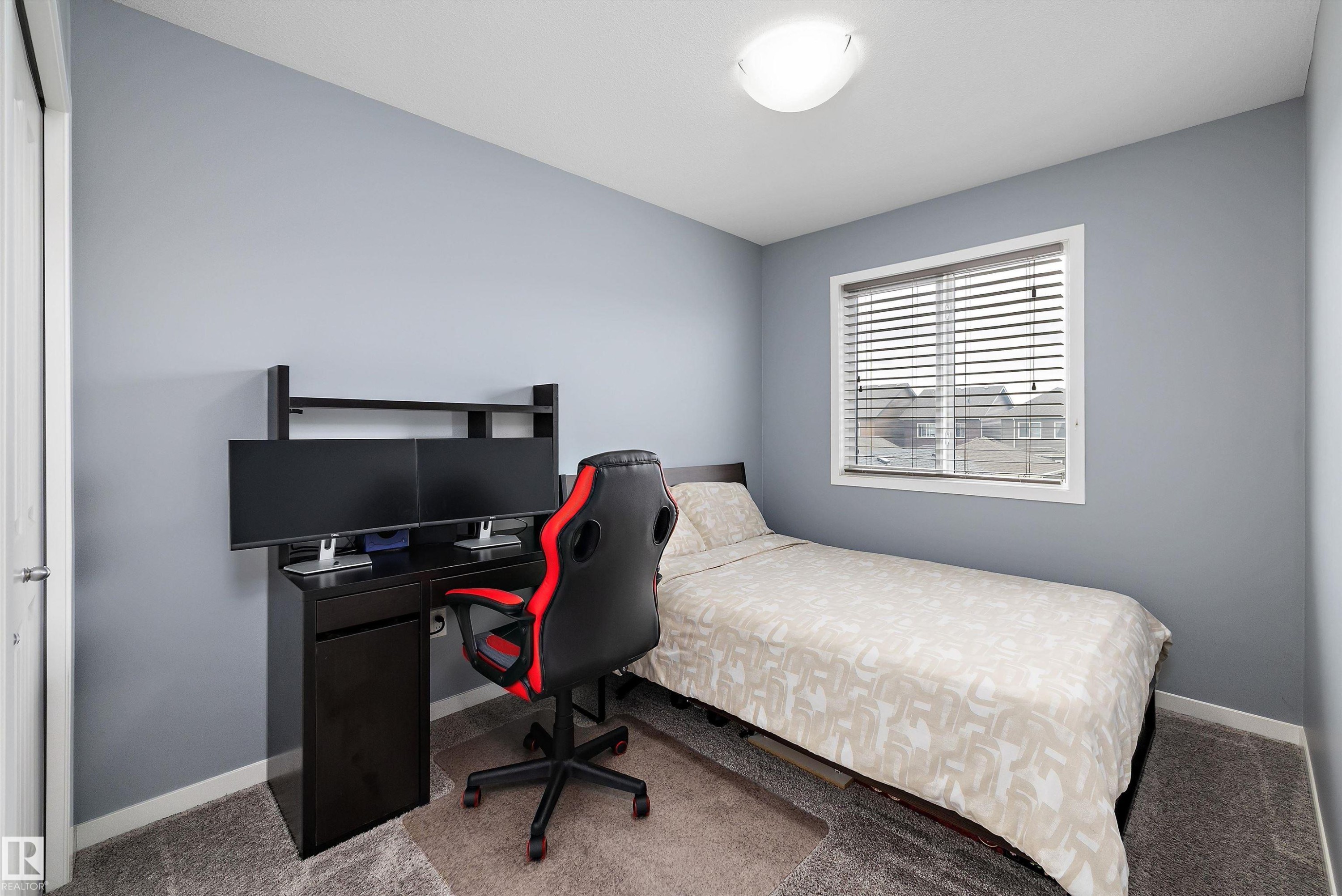 Bedroom featuring light gray walls, gray carpet flooring, and a white framed window with horizontal blinds - 2833 Chokecherry Place, Edmonton, AB