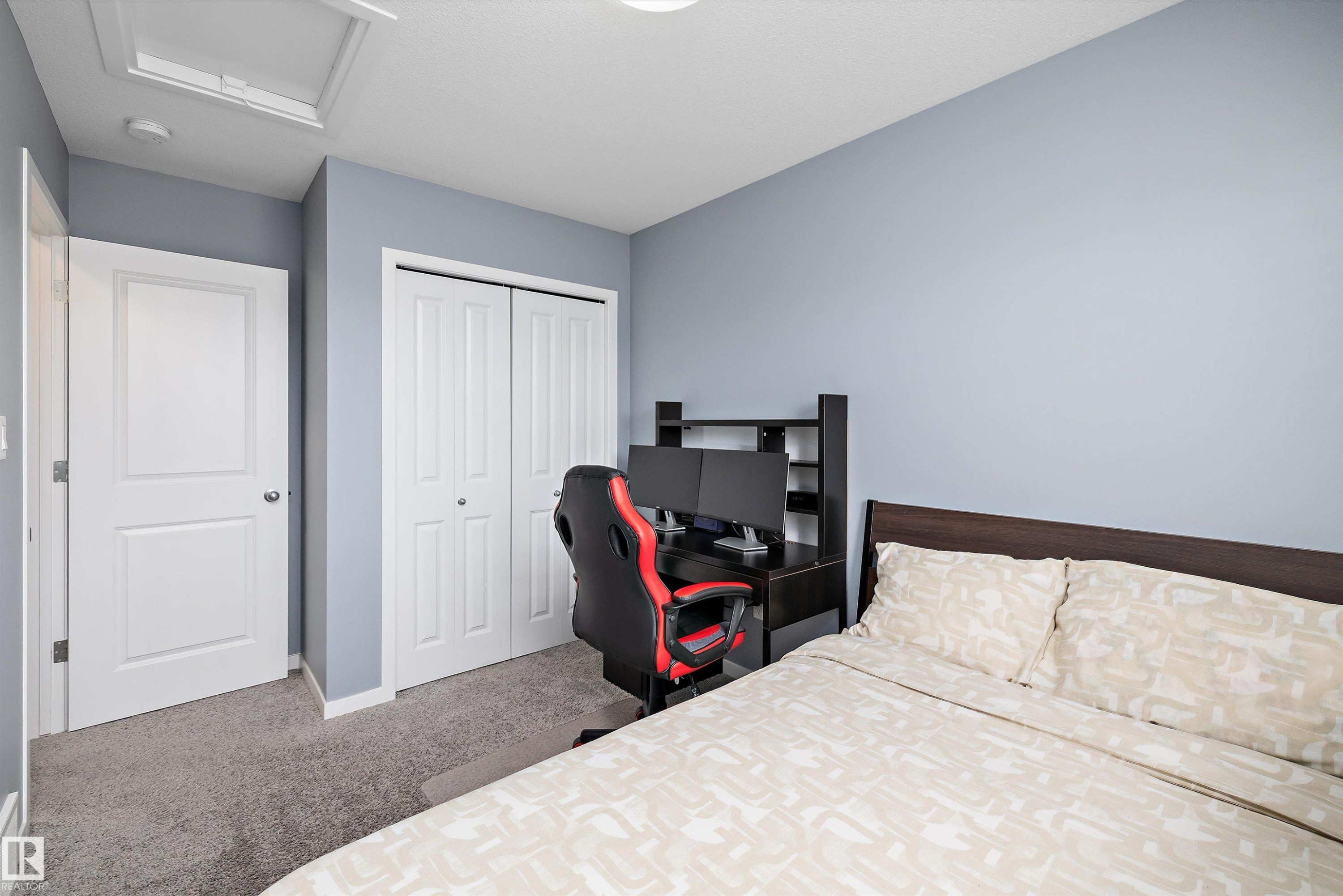 Bedroom featuring light blue walls, gray carpet, a white paneled door, and a white bi-fold closet - 2833 Chokecherry Place, Edmonton, AB