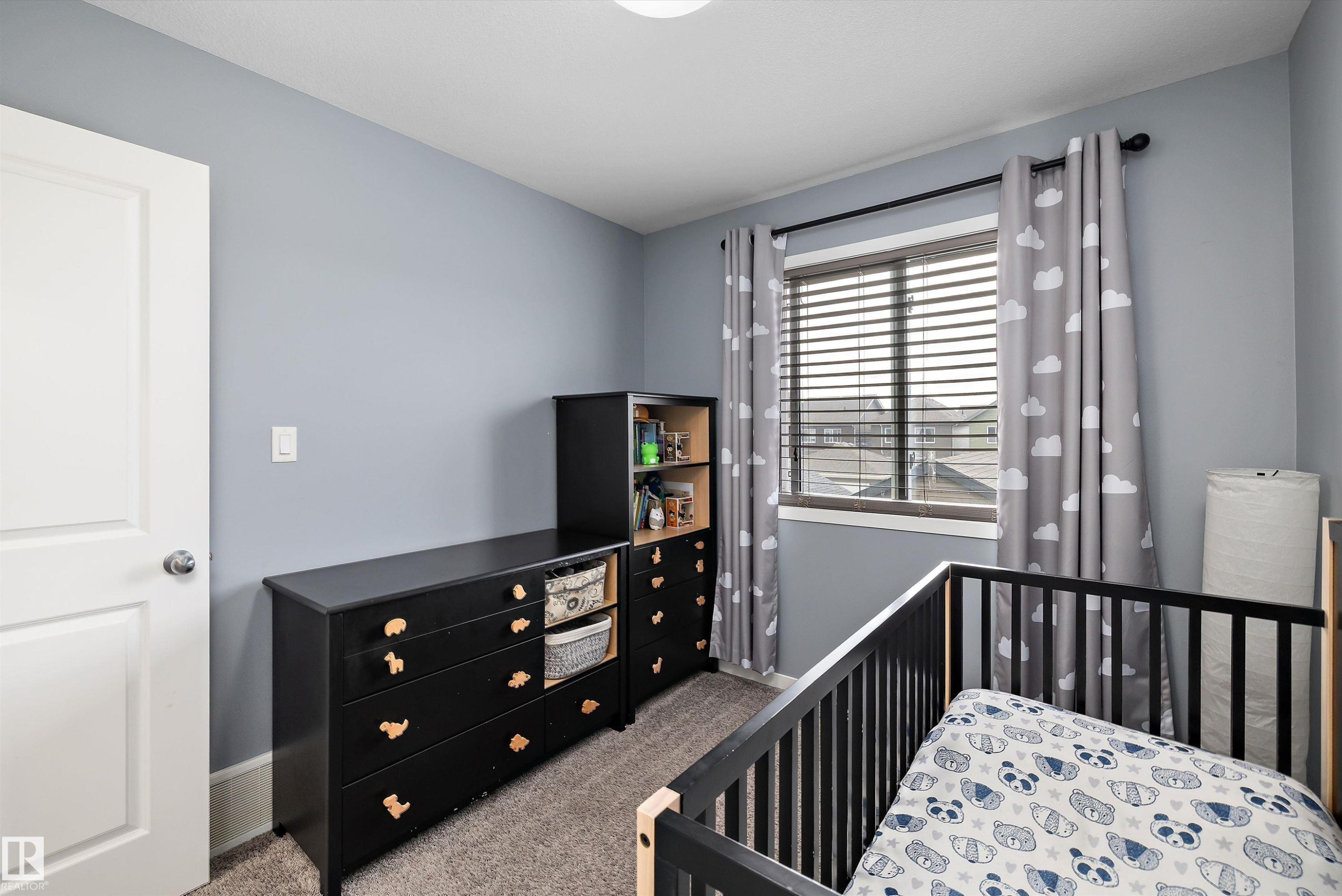 Light blue wall paint creating a neutral backdrop, white trim around the window, and textured carpeting - 2833 Chokecherry Place, Edmonton, AB
