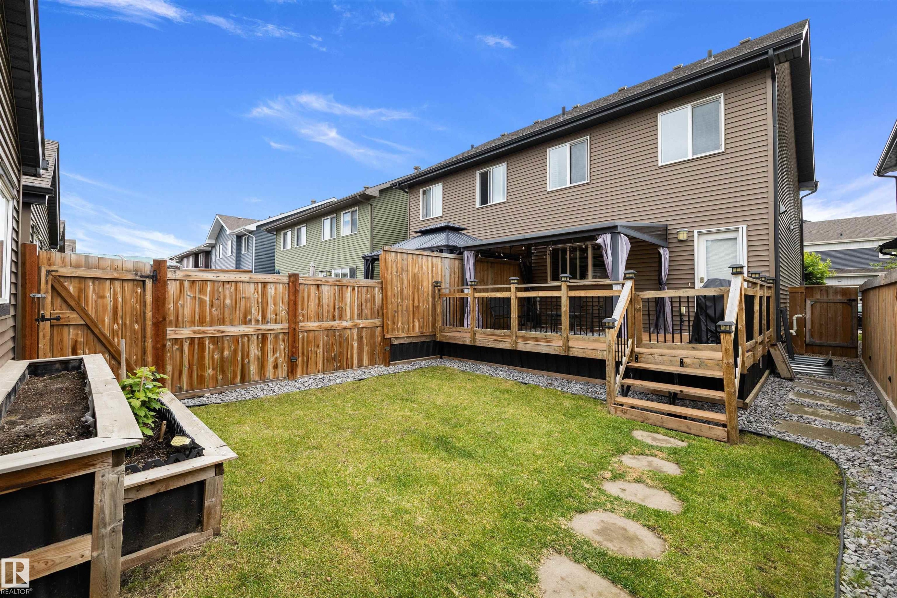 Expansive backyard featuring a manicured lawn, a raised garden bed, and a wooden privacy fence - 2833 Chokecherry Place, Edmonton, AB