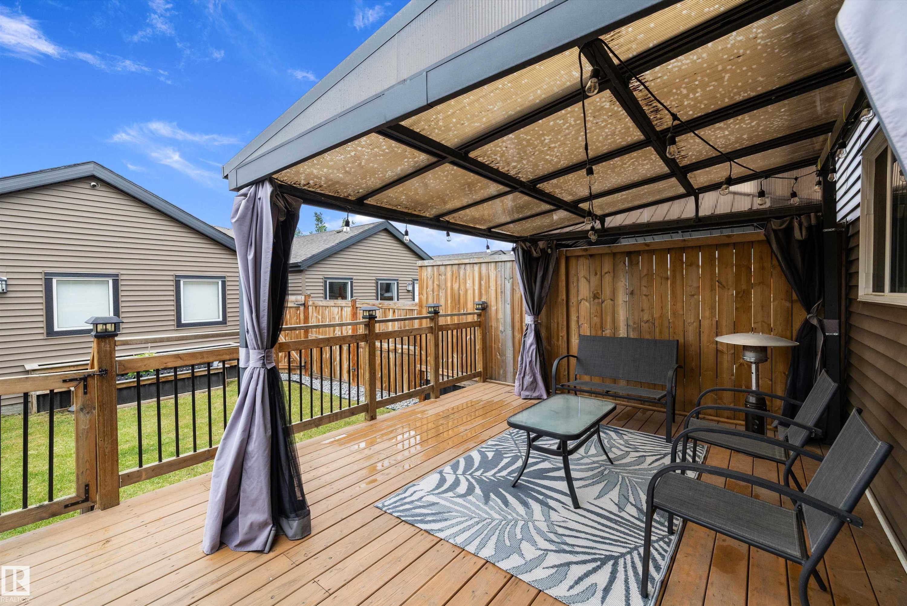 Expansive wood deck with a covered pergola featuring overhead string lighting - 2833 Chokecherry Place, Edmonton, AB