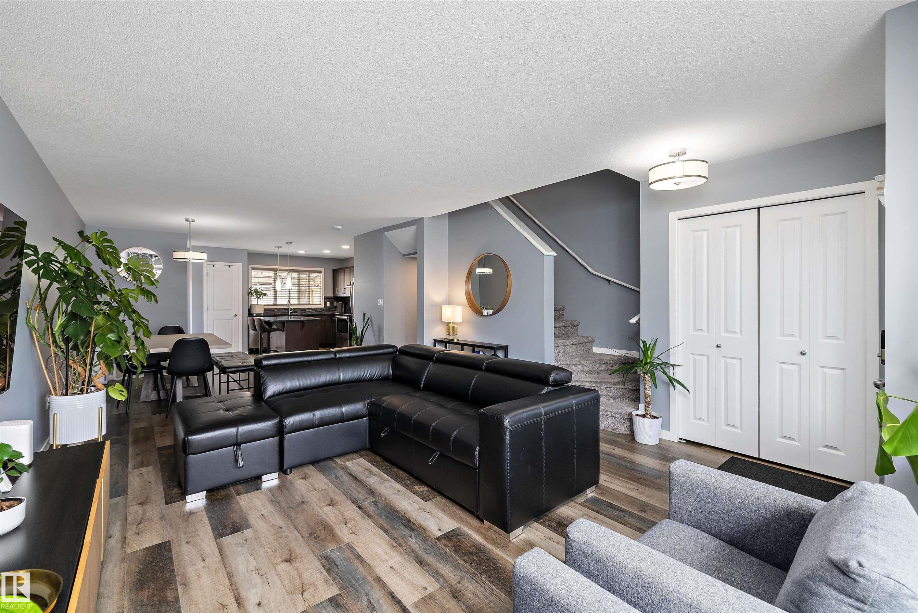 Spacious living area featuring wood-finish flooring, light gray walls, and white bi-fold doors - 2833 Chokecherry Place, Edmonton, AB