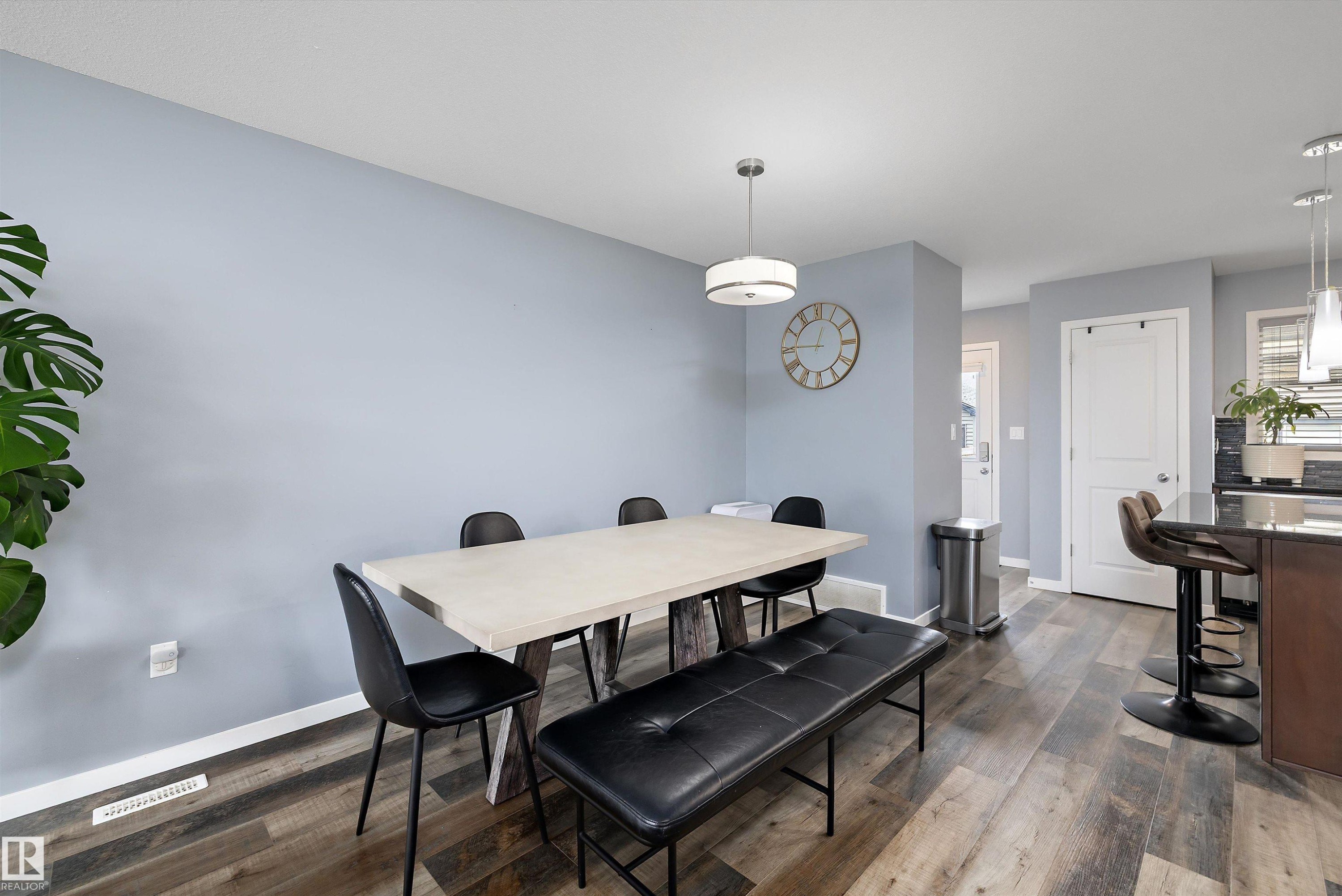 Dining area featuring wood-finish flooring, light blue wall paint, and a modern drum pendant light - 2833 Chokecherry Place, Edmonton, AB