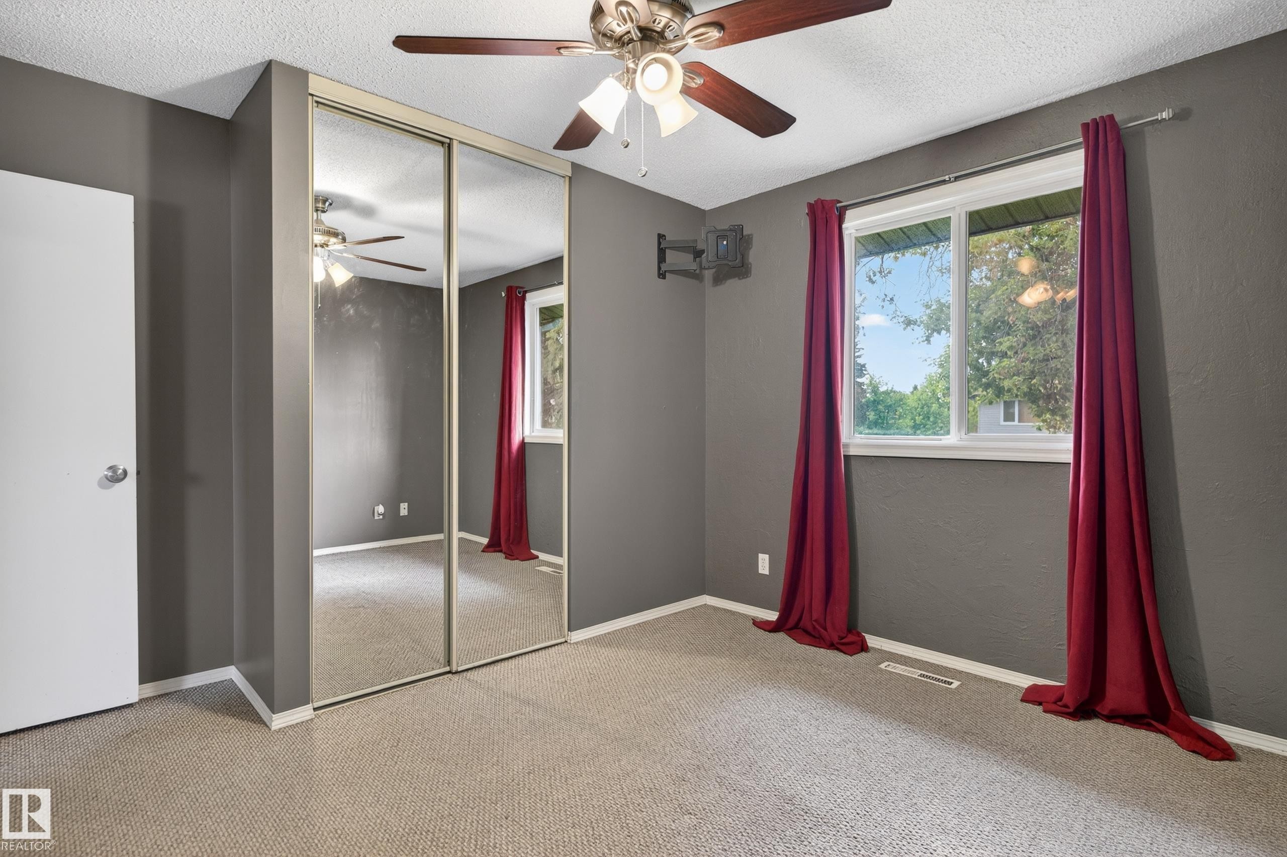 Room featuring light-colored carpet flooring, a ceiling fan with integrated lighting, and a window providing natural illumination - 13427 114 Street Nw, Edmonton, AB