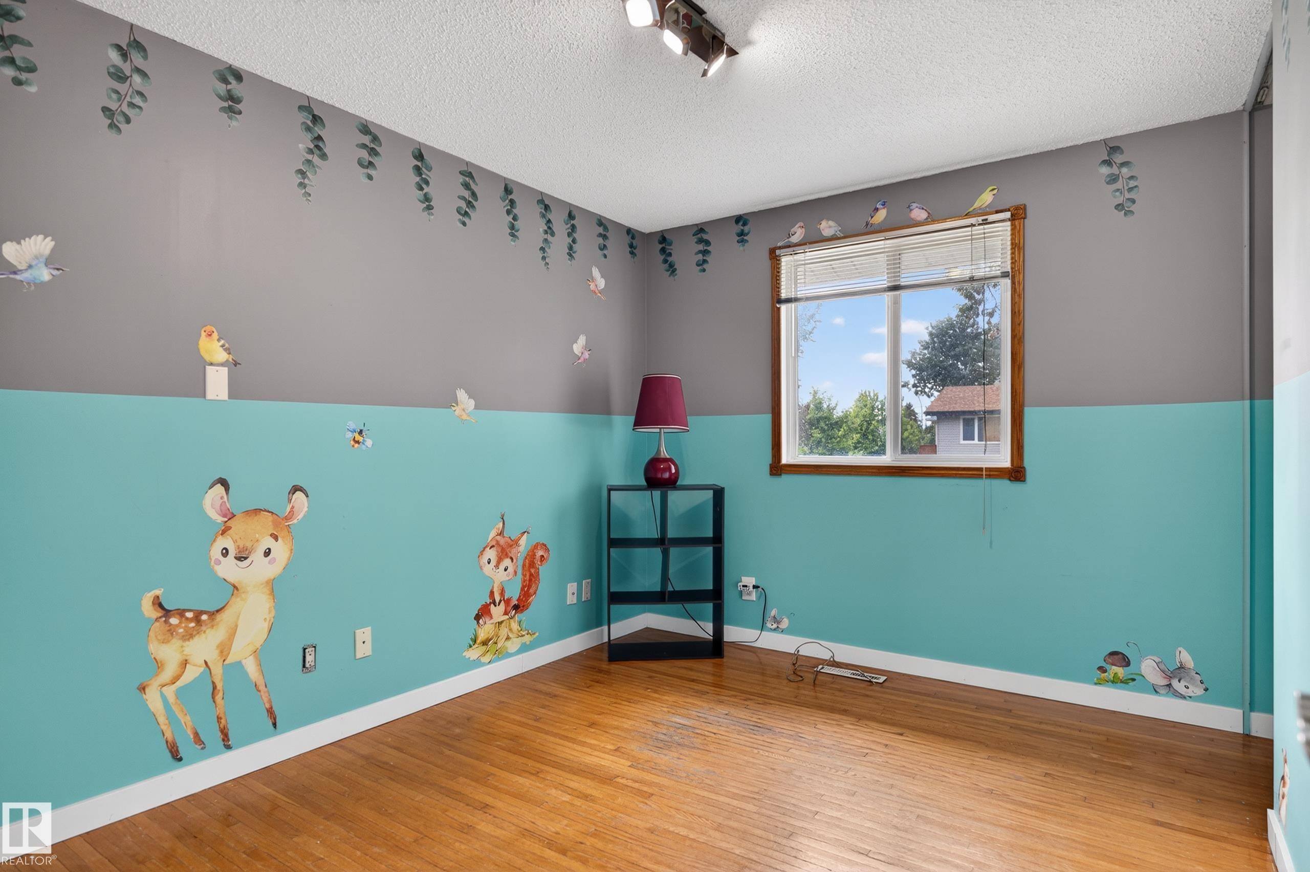Room featuring wood-finish flooring, a double-hung window, two-tone painted walls, and a textured ceiling - 13427 114 Street Nw, Edmonton, AB