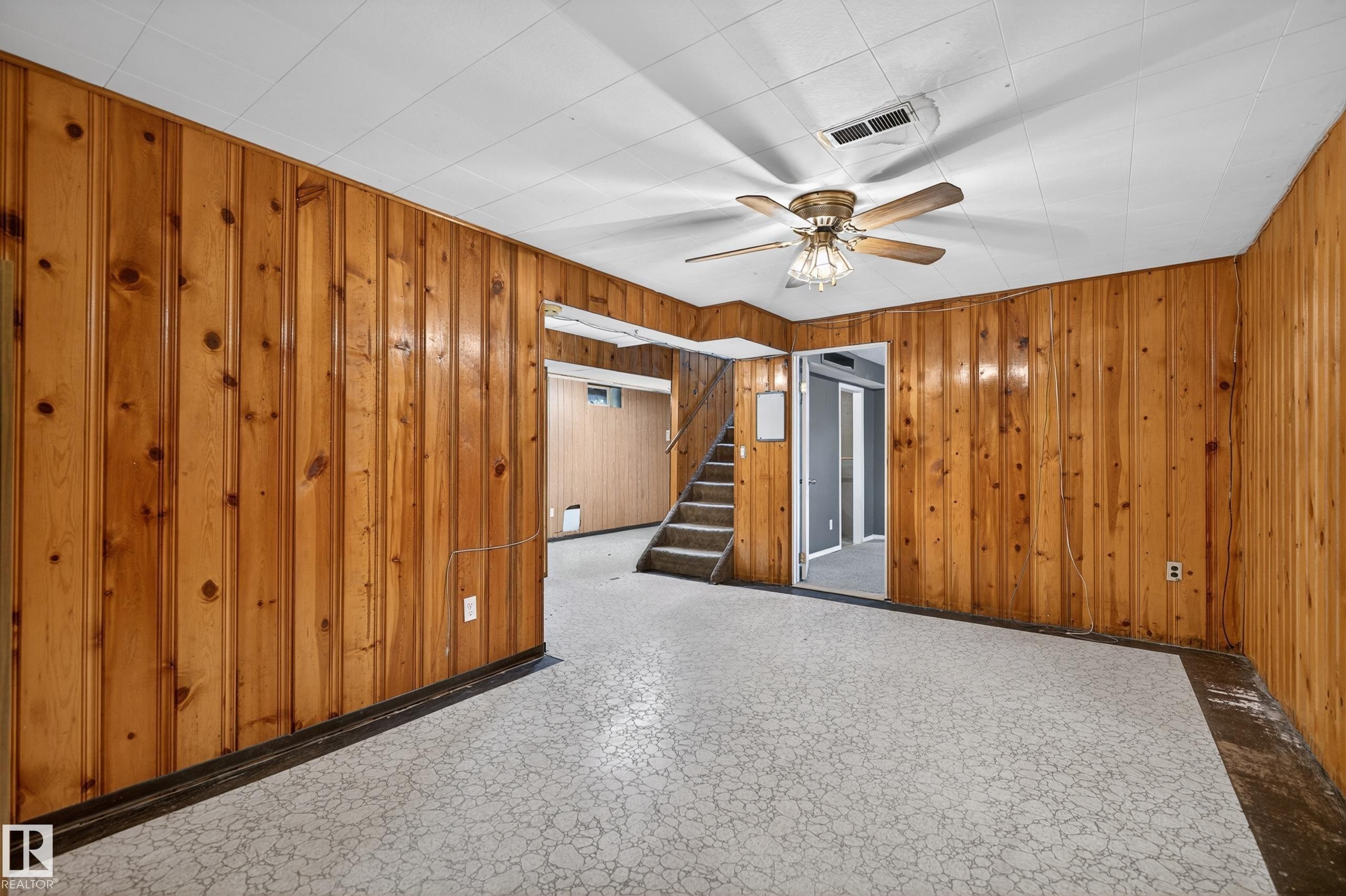 Room featuring wood paneling, a patterned ceiling, and a ceiling fan with light fixture - 13427 114 Street Nw, Edmonton, AB