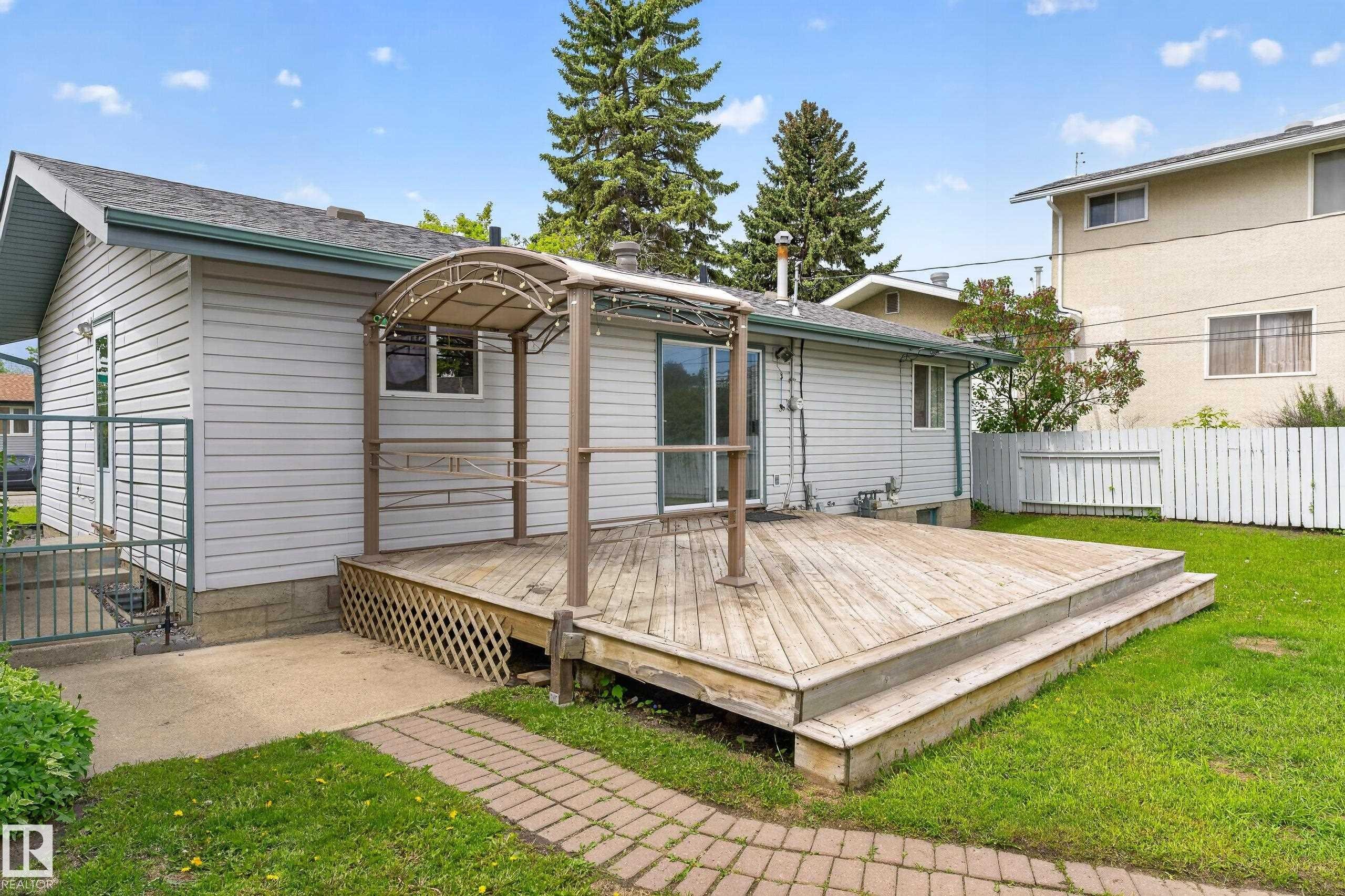 Expansive wood deck with a built-in pergola, offering direct access to the interior via sliding glass doors - 13427 114 Street Nw, Edmonton, AB