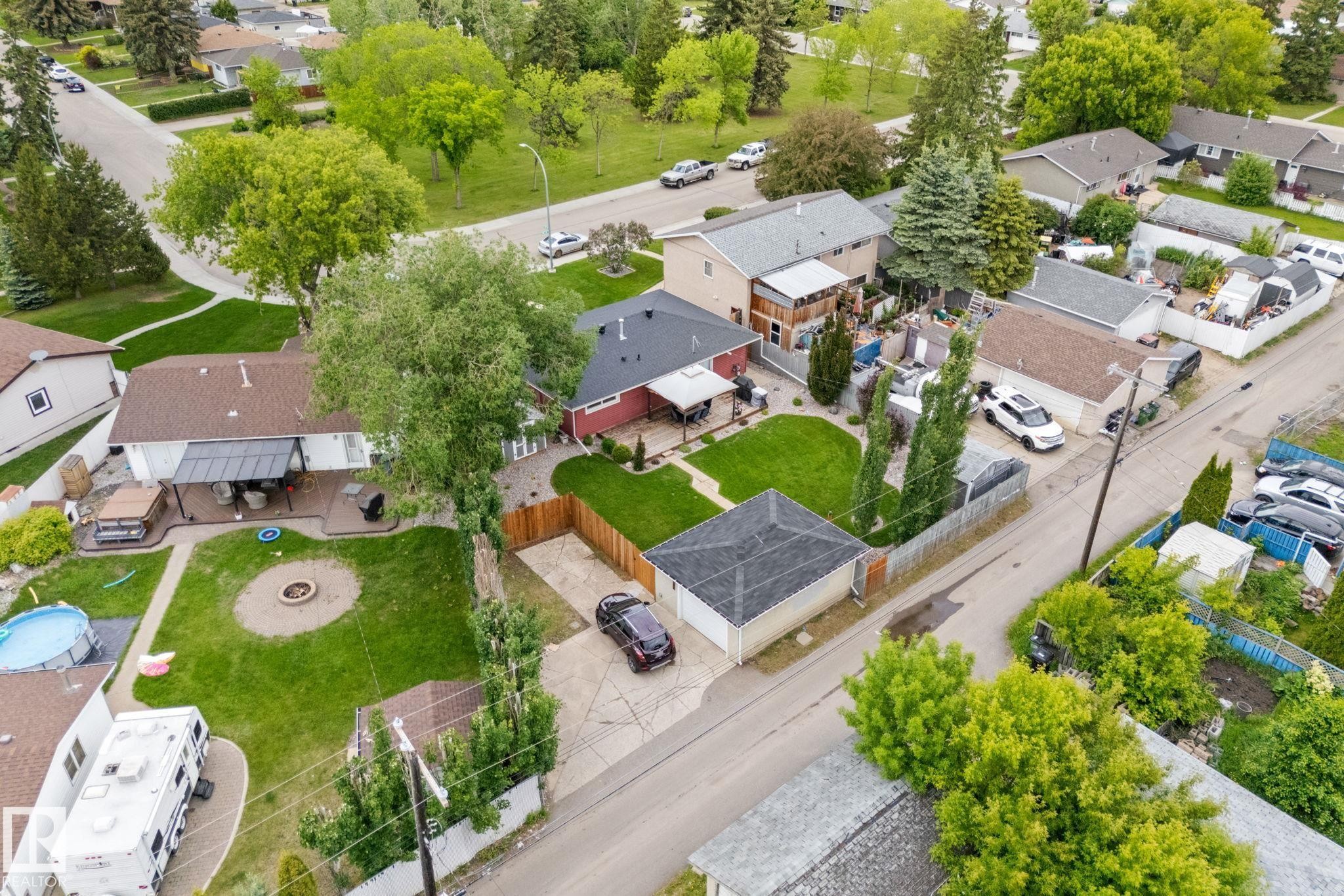 Expansive property featuring a detached garage, a fenced backyard with a fire pit area, and a paved driveway offering off-street parking - 11219 134A Avenue, Edmonton, AB