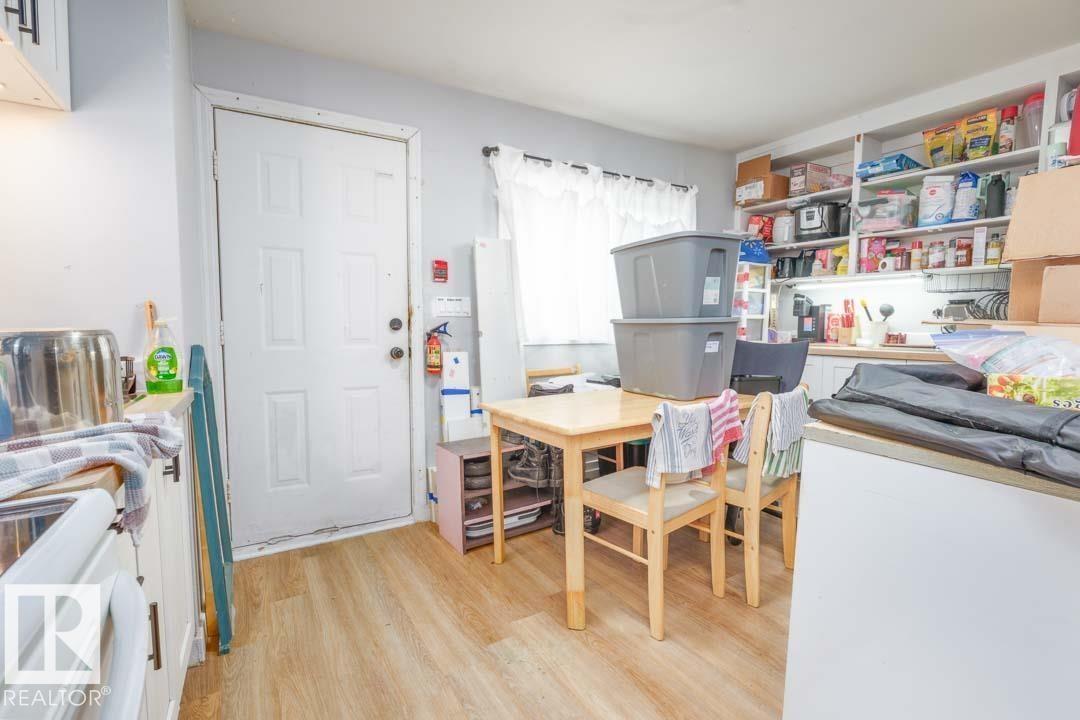 Kitchen area featuring wood-finish flooring, white cabinetry, integrated sink, and open shelving - 11308 94 Street, Edmonton, AB