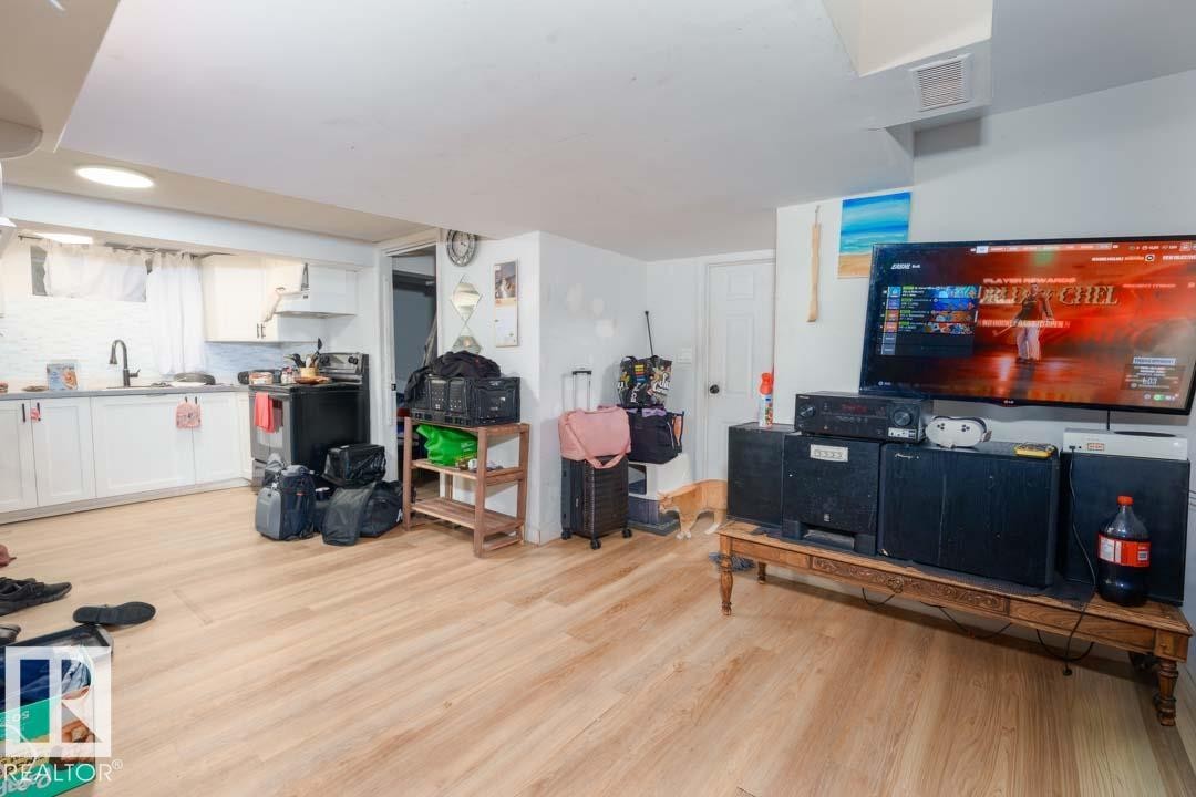 Open-concept living area with wood-finish flooring, recessed lighting, and a white ceiling - 11308 94 Street, Edmonton, AB