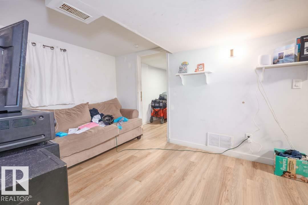 Room featuring wood-finish flooring, white painted walls, and an overhead air vent - 11308 94 Street, Edmonton, AB