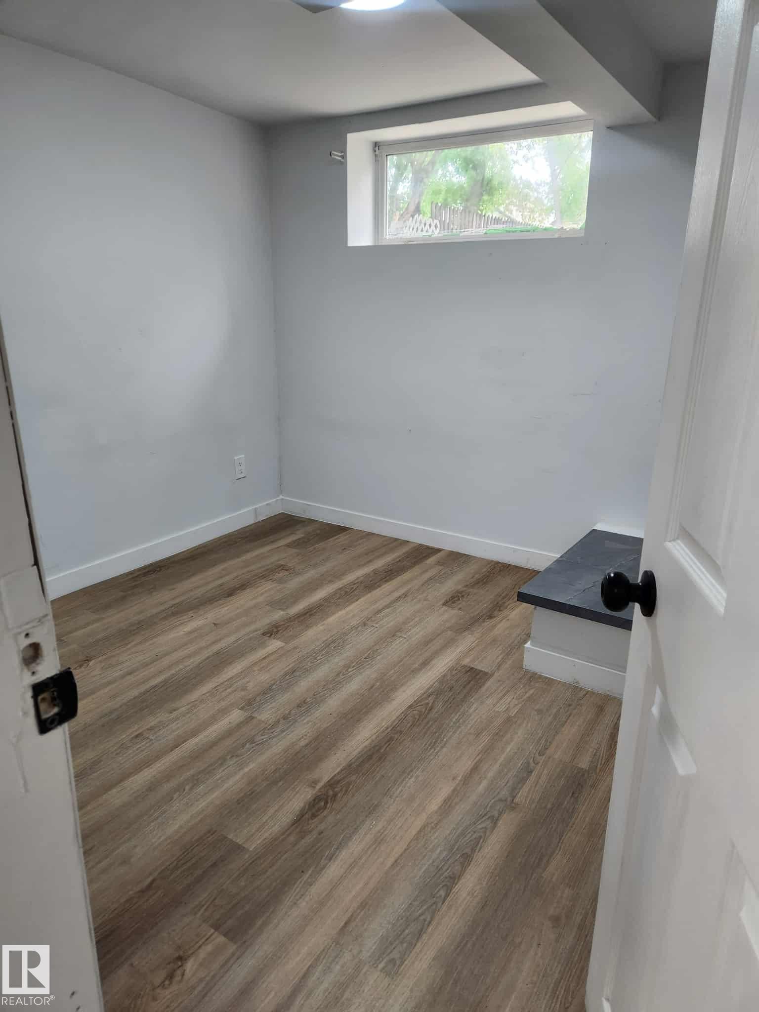 Room featuring wood-finish flooring, white baseboards, and light gray walls - 11308 94 Street, Edmonton, AB