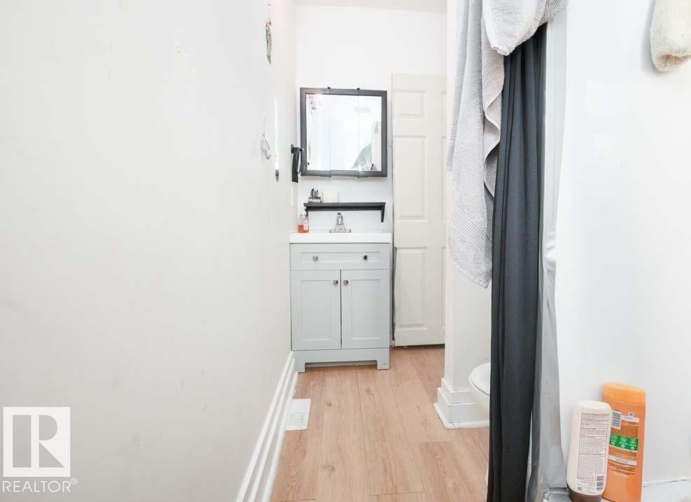 Bathroom featuring a light-colored vanity with a white countertop and a rectangular mirror with a dark frame - 11308 94 Street, Edmonton, AB