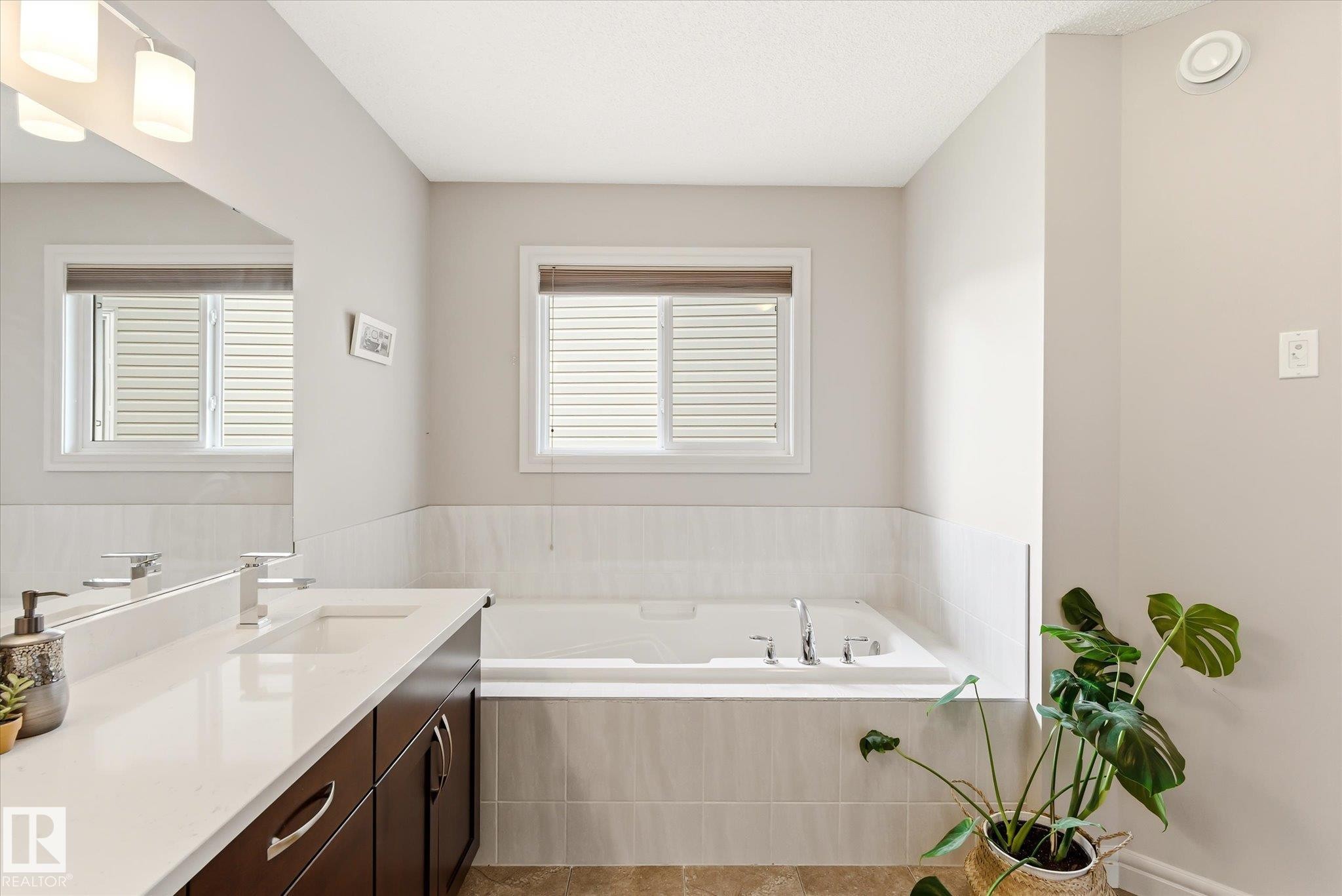 Spa-like bathroom with a built-in soaking tub featuring chrome fixtures and a tiled surround - 3685 Westcliff Way, Edmonton, AB