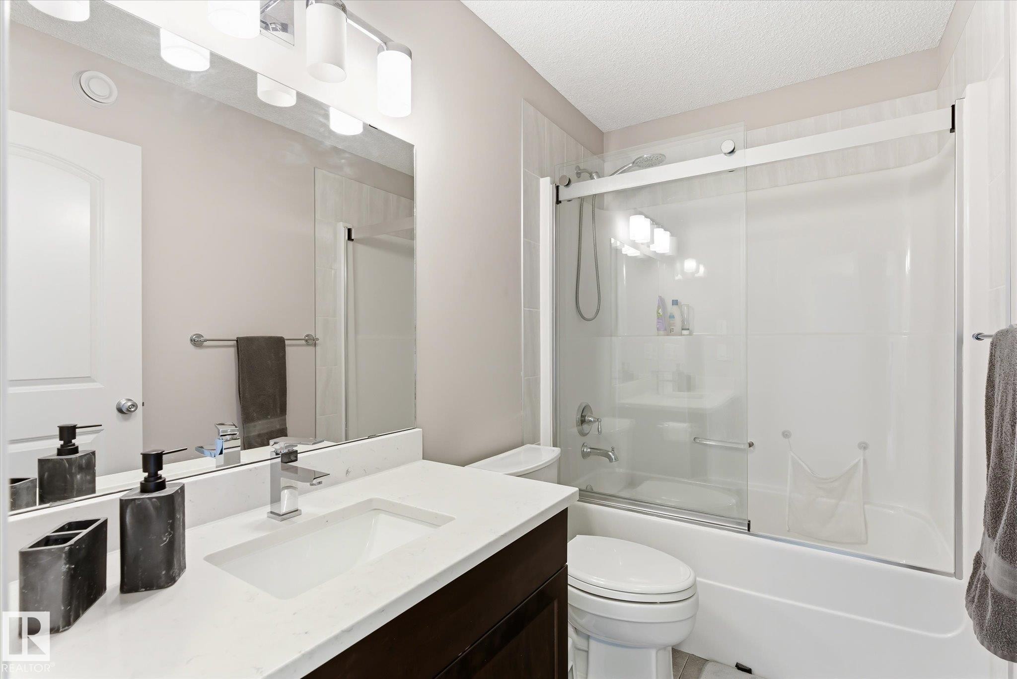 Bathroom featuring a white vanity with an integrated sink, polished chrome faucet, and quartz countertop - 3685 Westcliff Way, Edmonton, AB