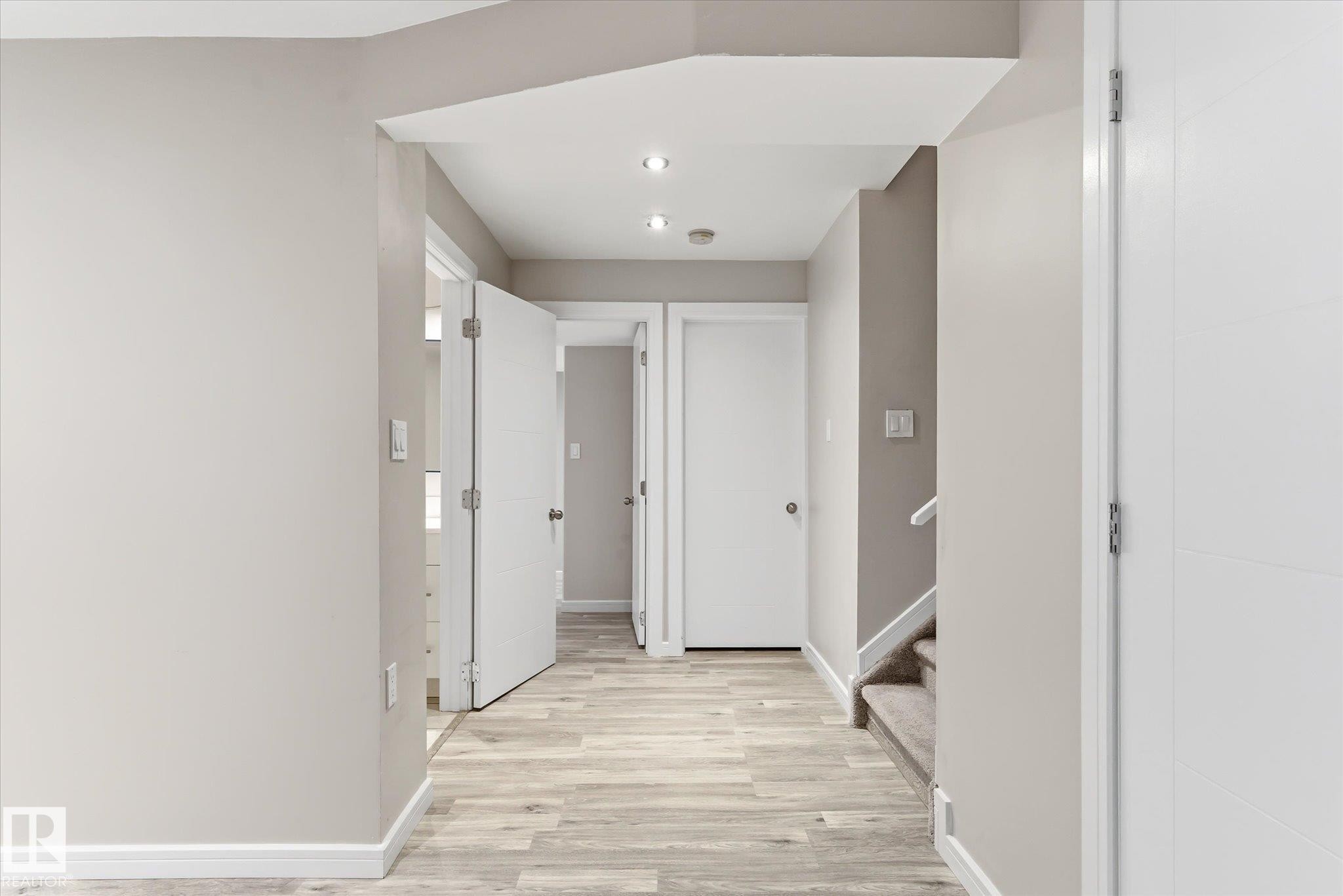 Hallway featuring wood-finish flooring, recessed lighting, neutral wall paint, white trim, and white interior doors - 3685 Westcliff Way, Edmonton, AB