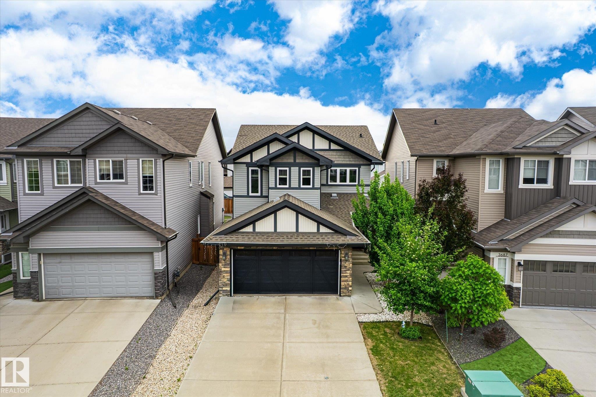 Two-story residence featuring a dark asphalt shingle roof and a two-car attached garage with a black door - 3685 Westcliff Way, Edmonton, AB