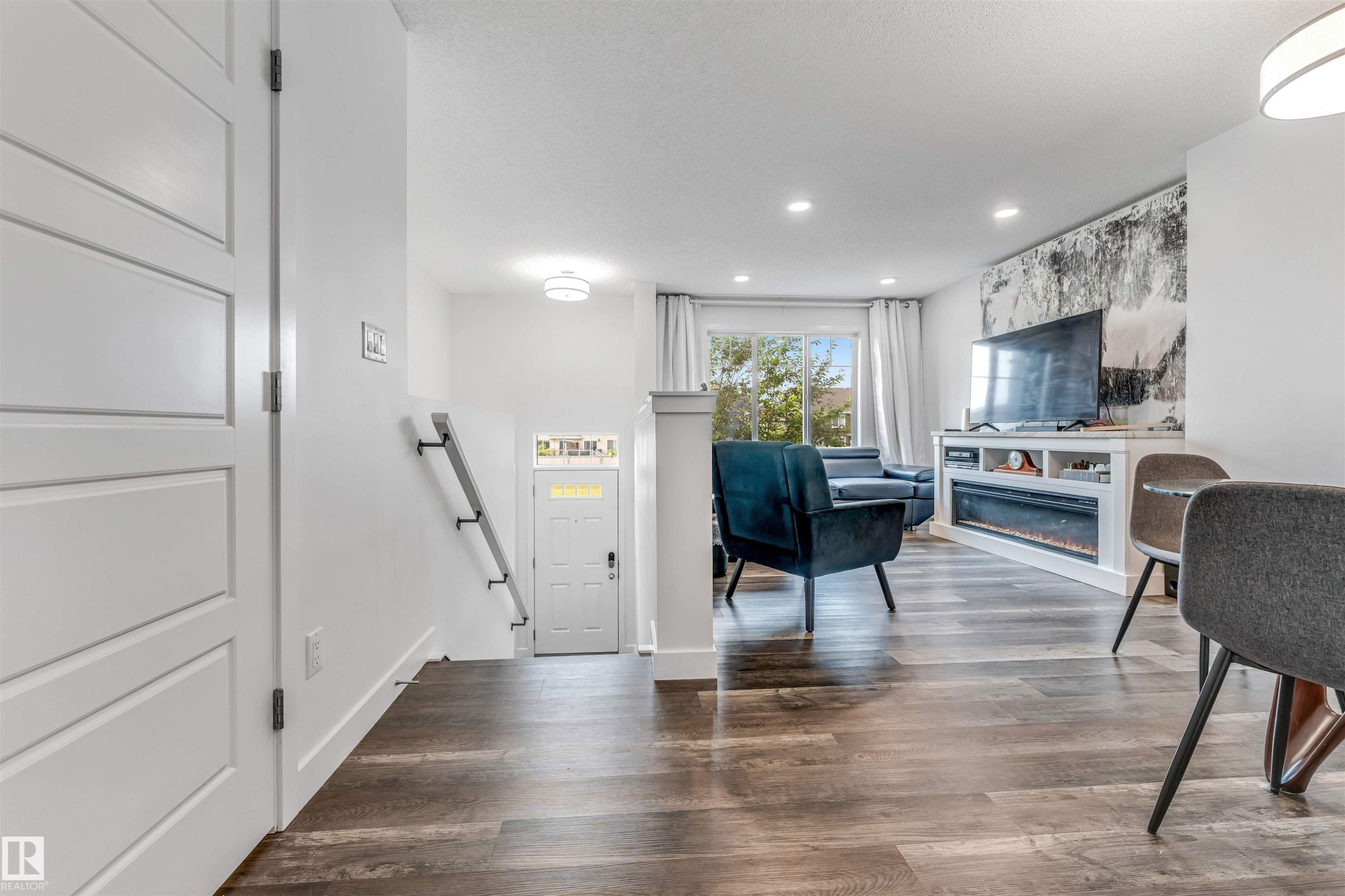 Open-concept living area featuring wood-finish flooring, recessed lighting, and a built-in media console with an electric fireplace - 116 3305 Orchards Link Sw, Edmonton, AB