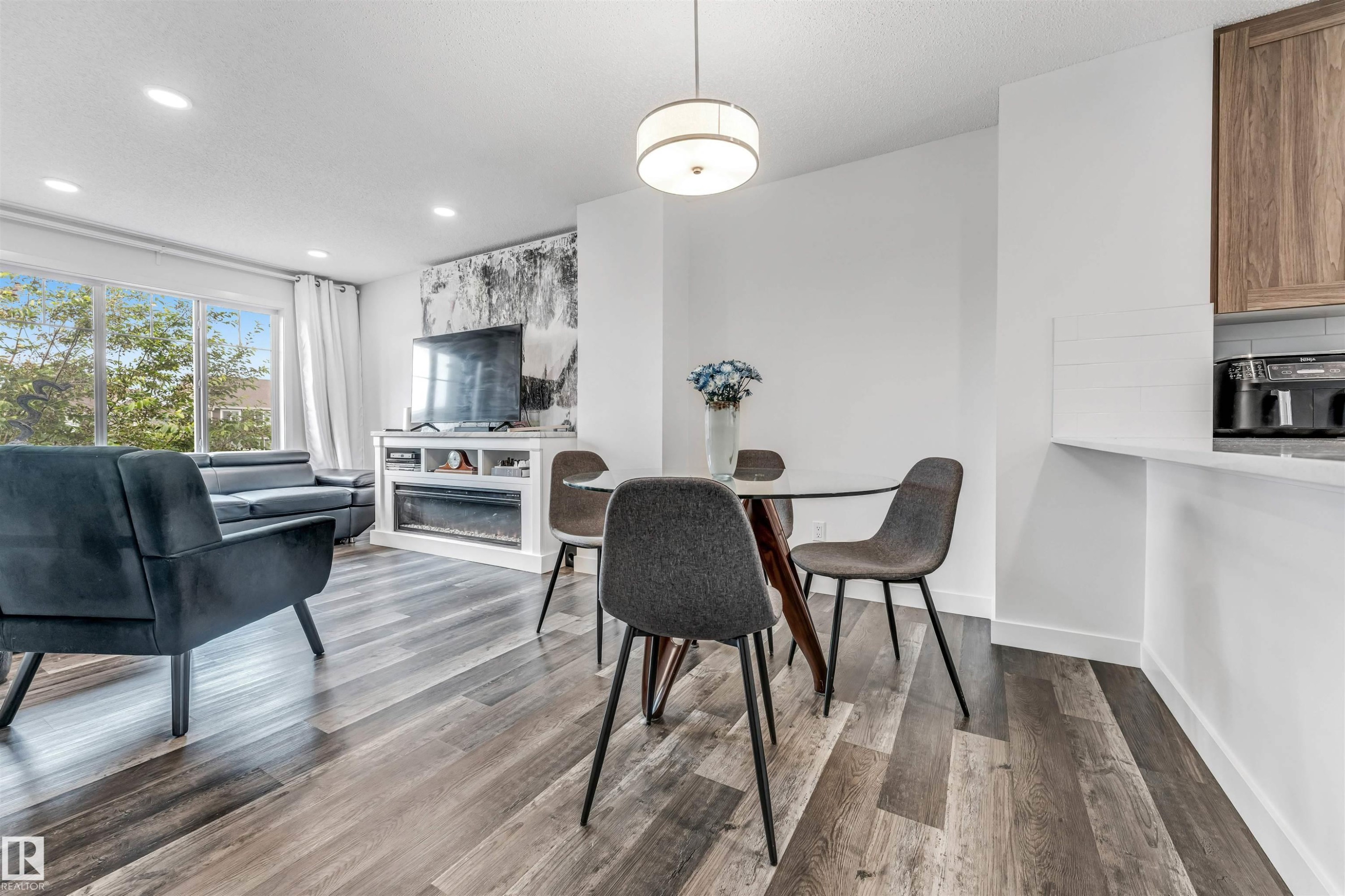 Open-concept living area featuring wood-finish flooring, a contemporary ceiling light fixture, and recessed lighting - 116 3305 Orchards Link Sw, Edmonton, AB