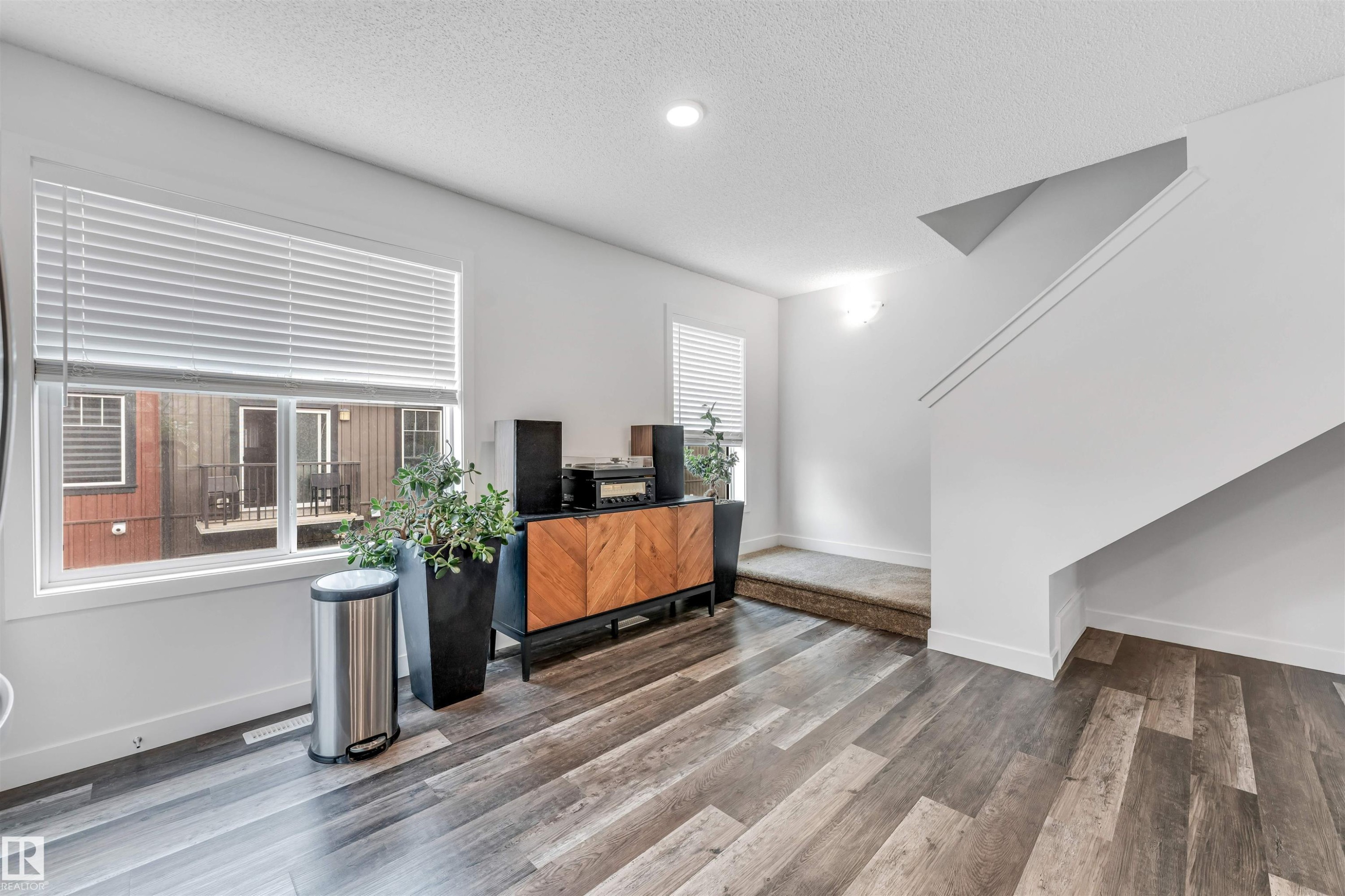 Interior with durable wood-finish flooring, white painted walls, and a contemporary open staircase - 116 3305 Orchards Link Sw, Edmonton, AB