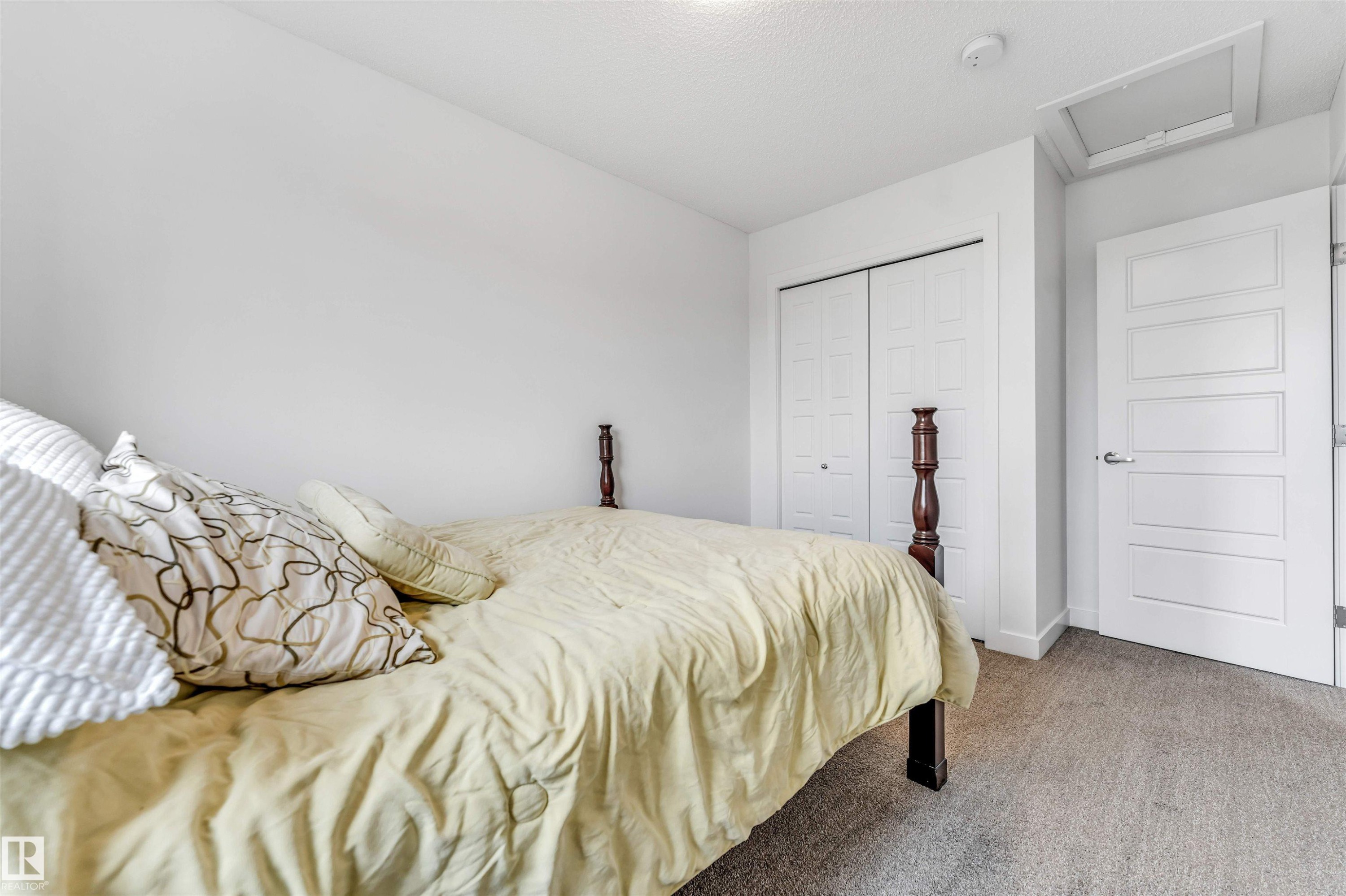 Light-toned wall finishes, neutral carpeting, and a white paneled door - 116 3305 Orchards Link Sw, Edmonton, AB