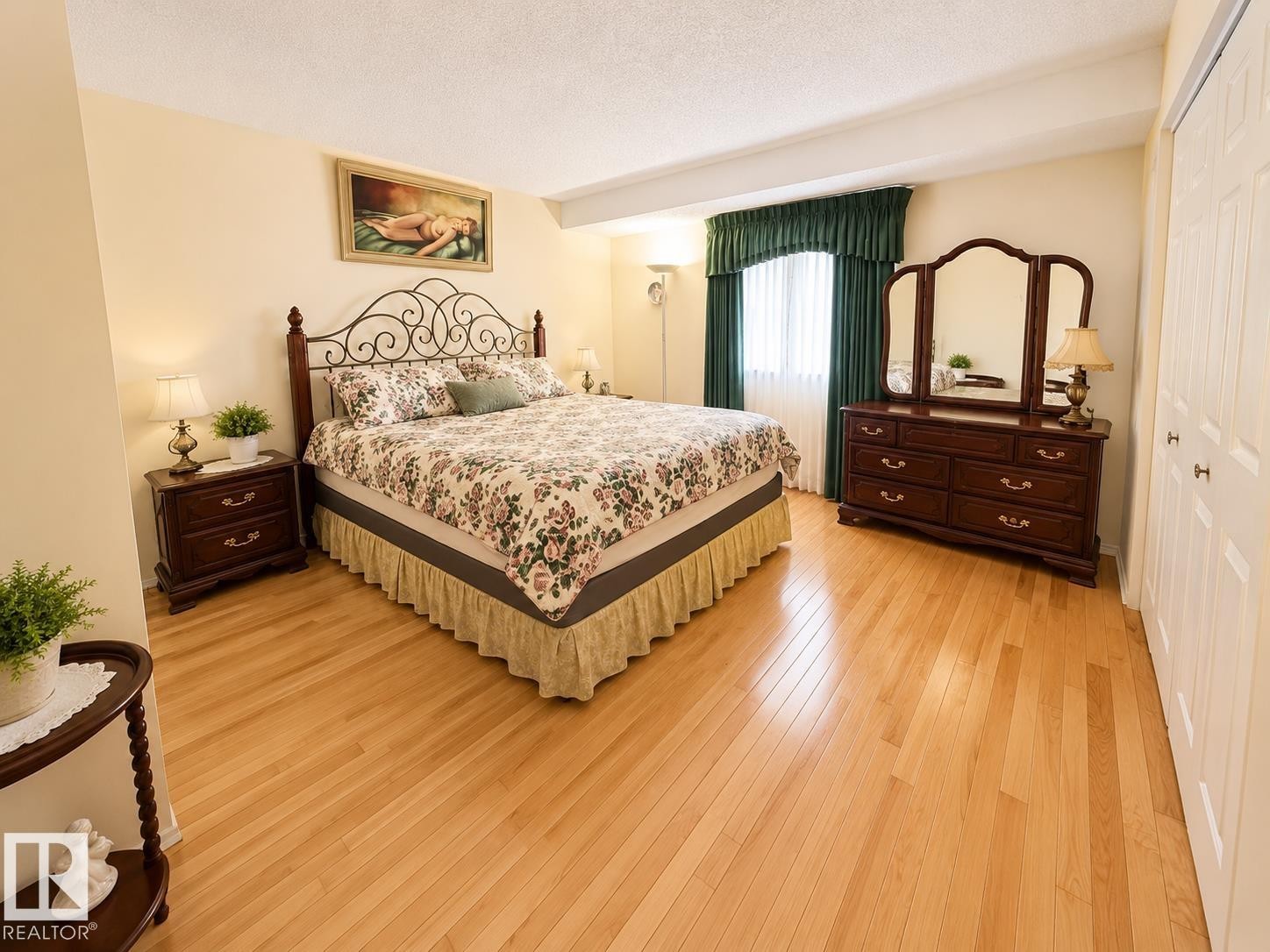 Bedroom featuring wood-finish flooring, a window with drapery, and a bifold closet door - 1 Munro Court, Leduc, AB