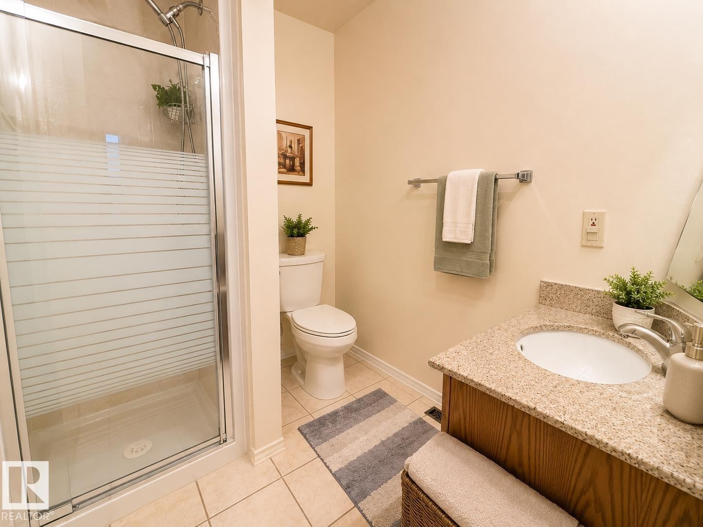 Bathroom featuring a shower with a frosted glass door, a toilet, and a vanity with a granite-style countertop and an integrated sink - 1 Munro Court, Leduc, AB