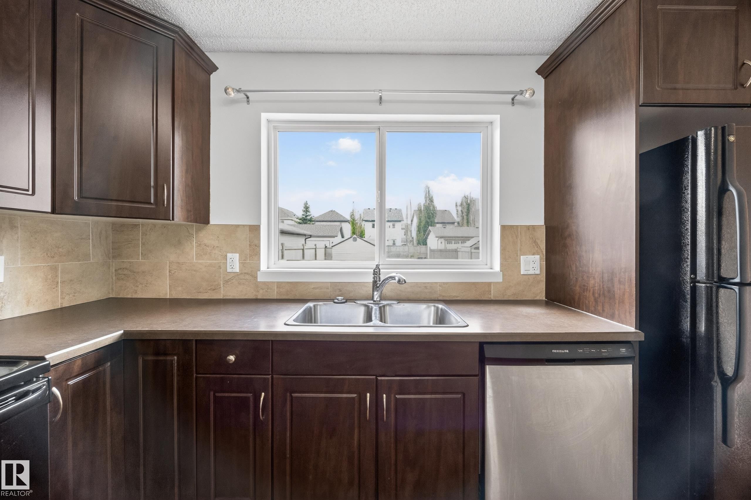 Kitchen featuring dark wood-finish cabinetry, a double basin stainless steel sink, and a tiled backsplash - 3634 12 Street, Edmonton, AB
