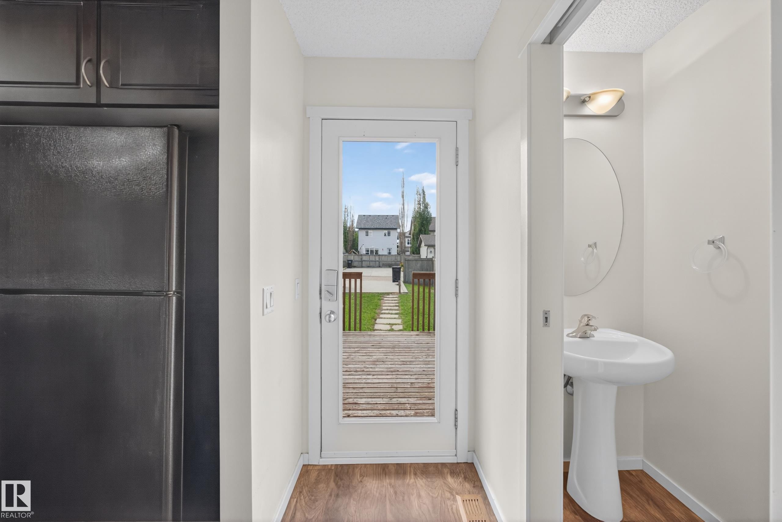 Glass-paneled exterior door opening to a wooden deck and grassy yard - 3634 12 Street, Edmonton, AB