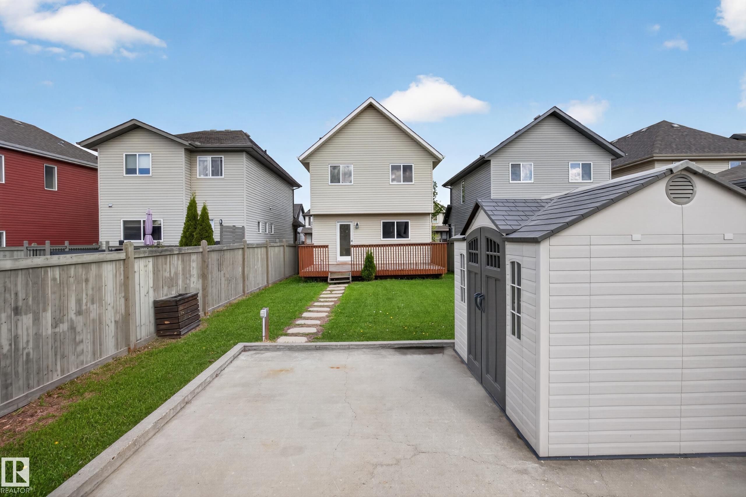 Manicured lawn with a stone pathway leading to a wood deck - 3634 12 Street, Edmonton, AB