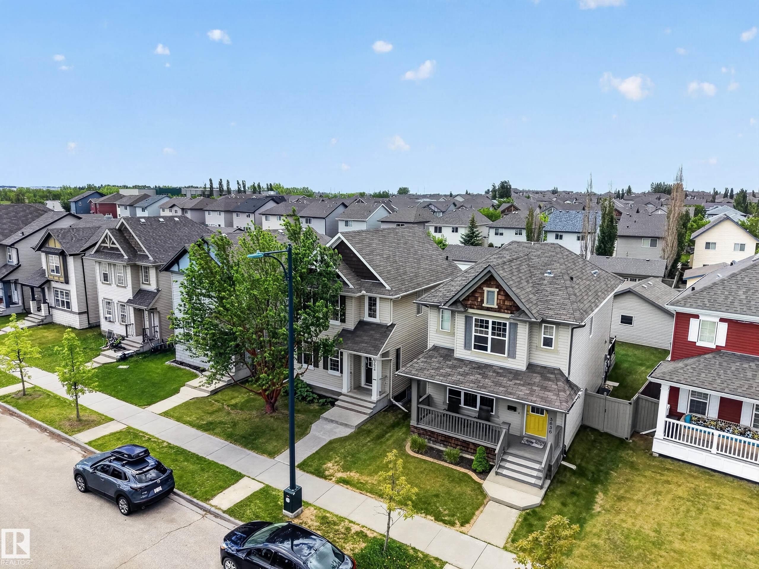 Two-story residence featuring a covered front porch, grey siding, and a distinctive yellow front door - 3634 12 Street, Edmonton, AB