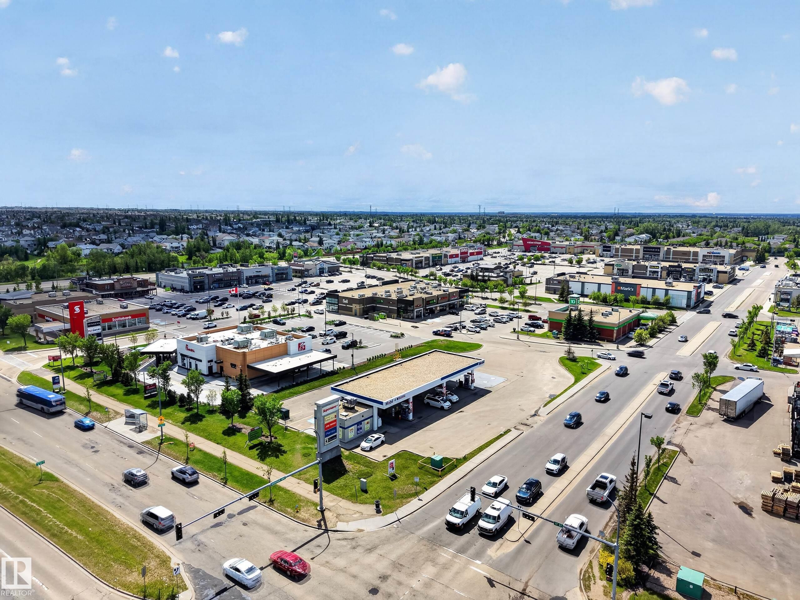 Aerial perspective showcasing a commercial district with multiple retail buildings, a gas station, and ample parking areas - 3634 12 Street, Edmonton, AB