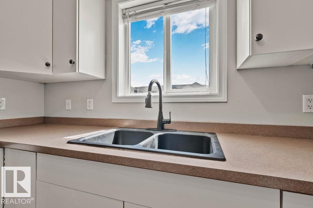 Kitchen sink area featuring a double basin sink with a matte black faucet - 232 4309 33 Street, Stony Plain, AB