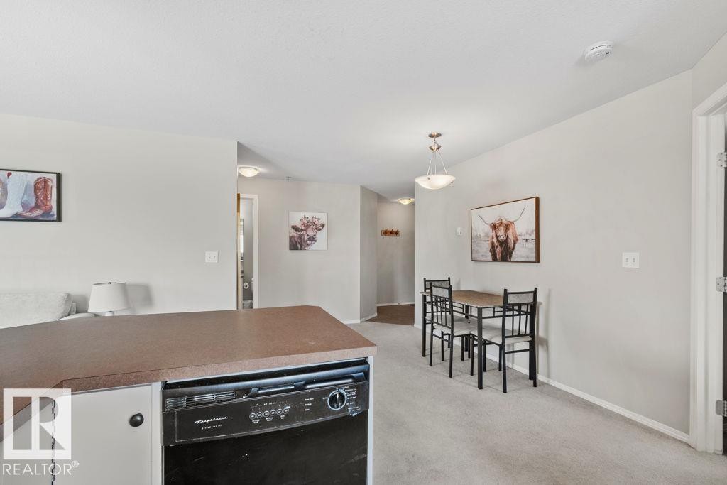 Kitchen island with laminate countertop, integrated black dishwasher, and white cabinetry - 232 4309 33 Street, Stony Plain, AB