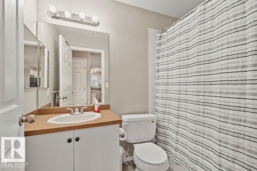 Bathroom featuring a built-in vanity with an integrated sink, a large wall-mounted mirror, and overhead strip lighting - 232 4309 33 Street, Stony Plain, AB