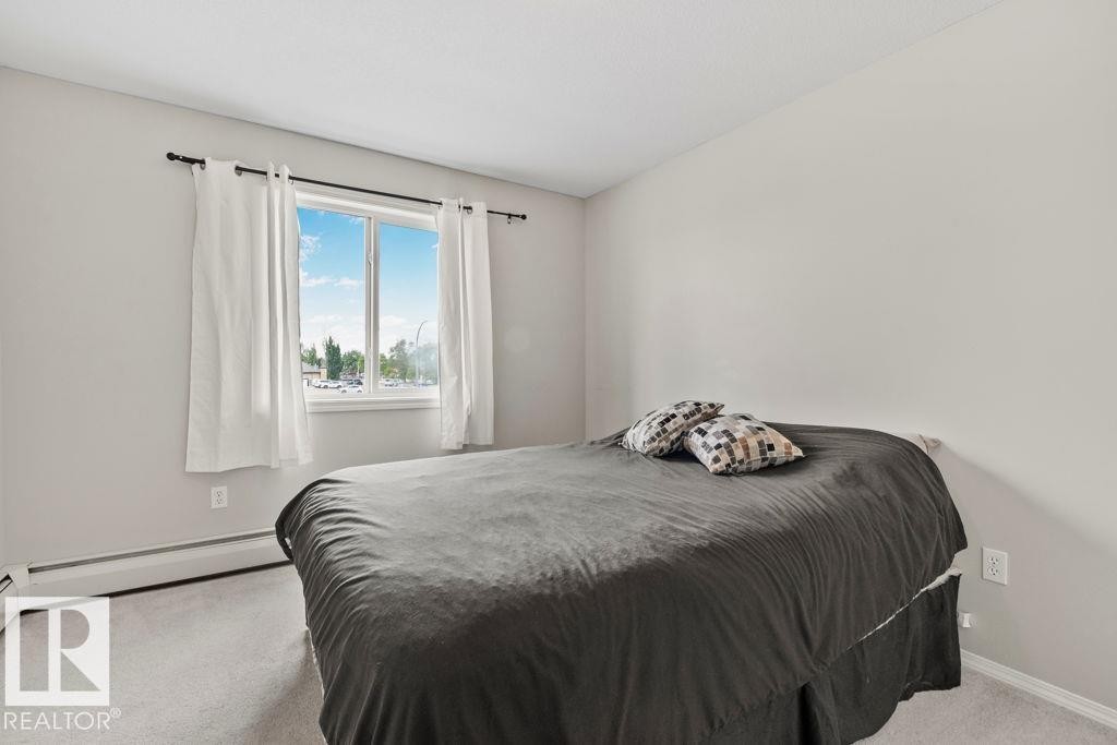 Carpeted room featuring a double-pane window, baseboard heating, and light-toned walls - 232 4309 33 Street, Stony Plain, AB