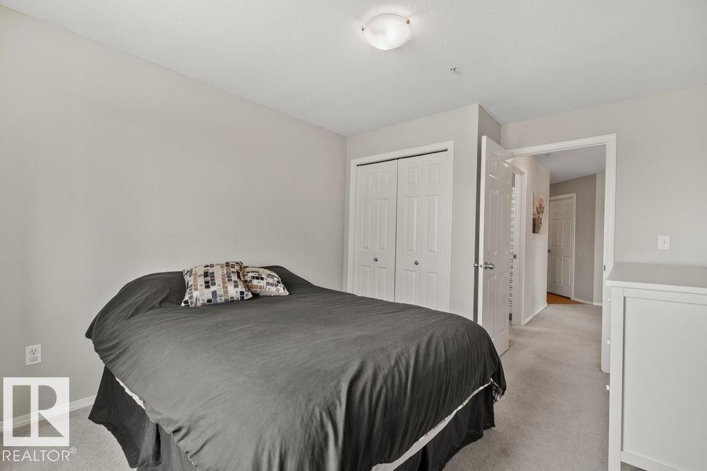 Carpeted room featuring light gray walls, a flush-mount ceiling light fixture, and white bi-fold closet doors - 232 4309 33 Street, Stony Plain, AB