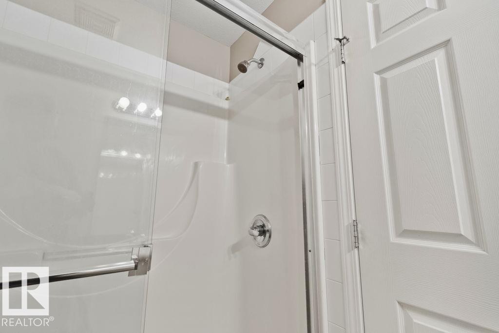 Shower enclosure featuring clear glass sliding doors and a chrome handle - 232 4309 33 Street, Stony Plain, AB