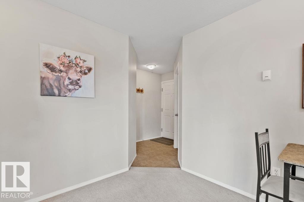 Open hallway with light gray walls, white baseboards, and neutral carpet flooring - 232 4309 33 Street, Stony Plain, AB