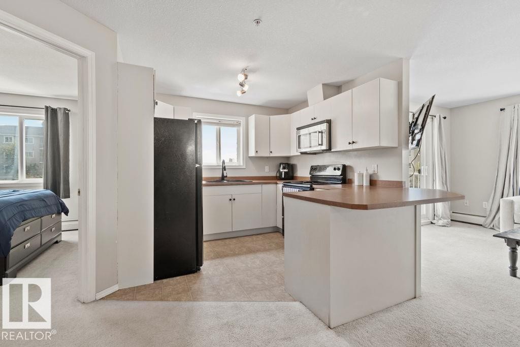 Kitchen featuring white cabinetry, dark countertops, and stainless steel appliances - 232 4309 33 Street, Stony Plain, AB