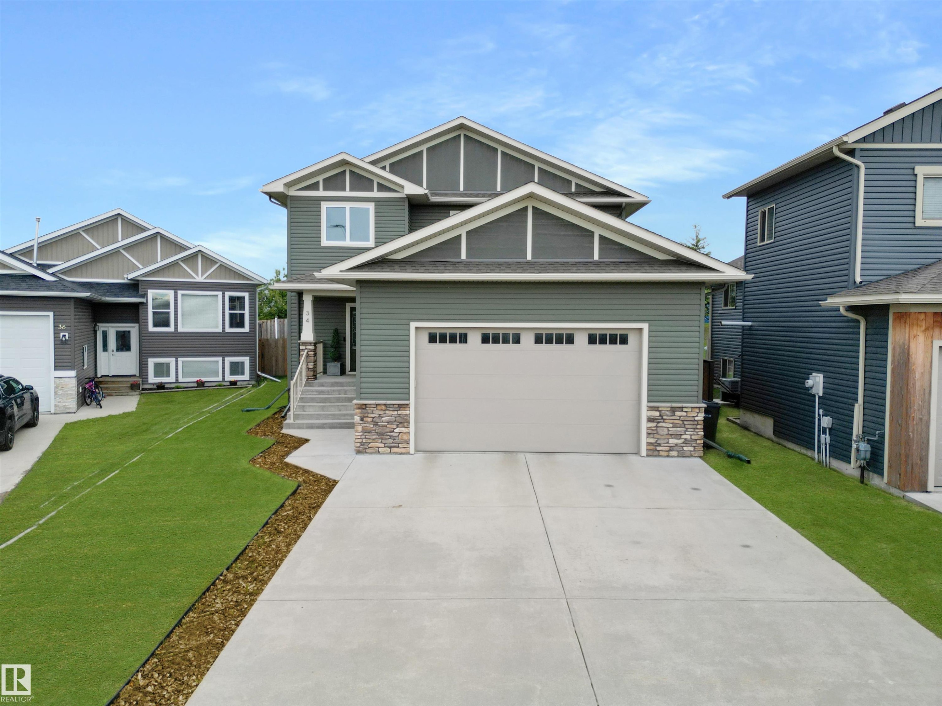 Modern two-story residence featuring a two-car garage, concrete driveway, and stone accents - 34 Falcon Road, Cold Lake, AB