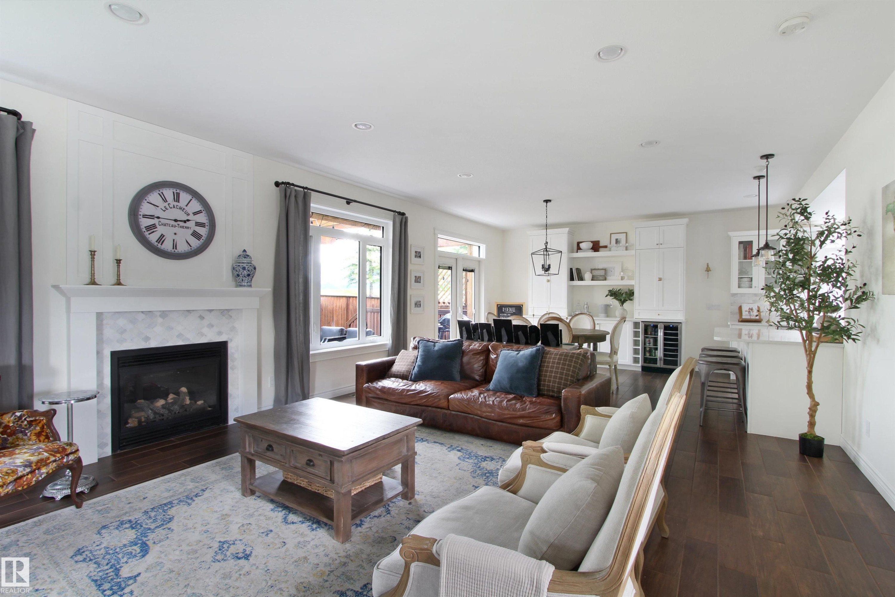 Living area featuring dark wood-finish flooring, a white mantel fireplace with a tiled surround, recessed lighting, and board and batten wall detailing - 34 Falcon Road, Cold Lake, AB
