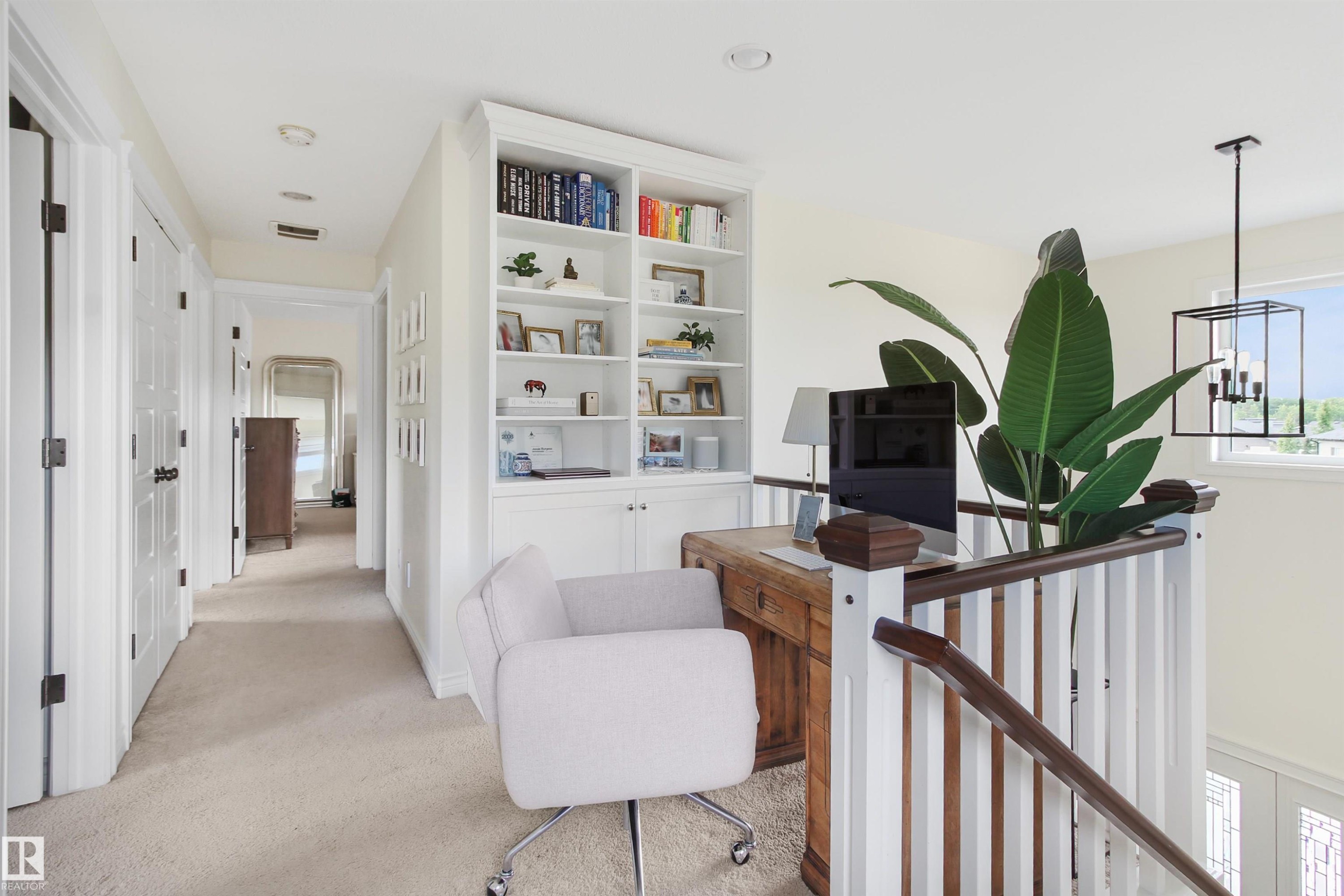 Integrated built-in shelving with lower cabinetry, light-toned carpet flooring, recessed ceiling lighting, a wood desk with dark wood accents, and a contemporary black metal chandelier with exposed bulbs - 34 Falcon Road, Cold Lake, AB