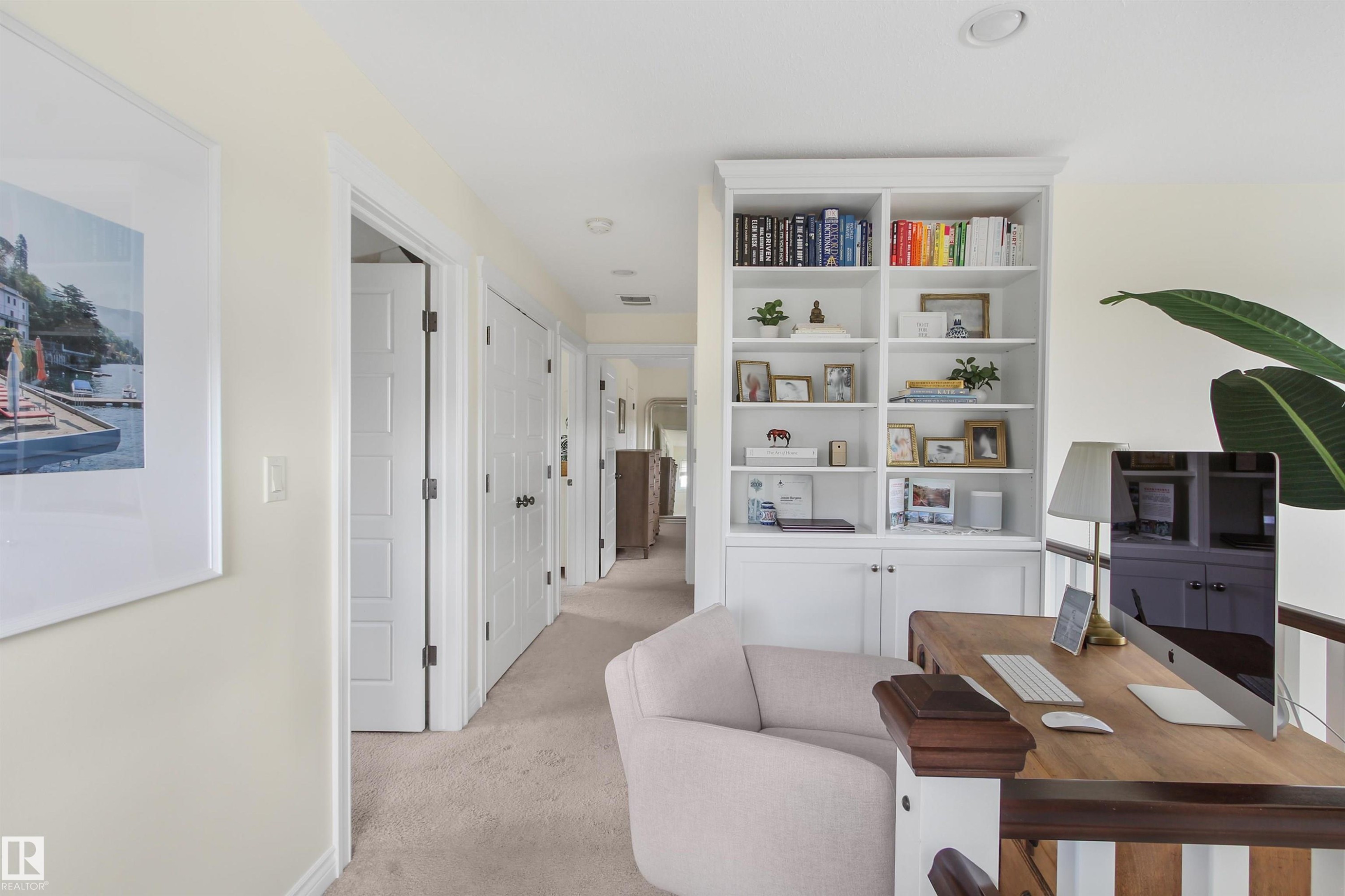 Built-in white shelving unit with lower cabinetry, recessed lighting, light beige carpeting, white paneled doors, and a wood-finish railing - 34 Falcon Road, Cold Lake, AB