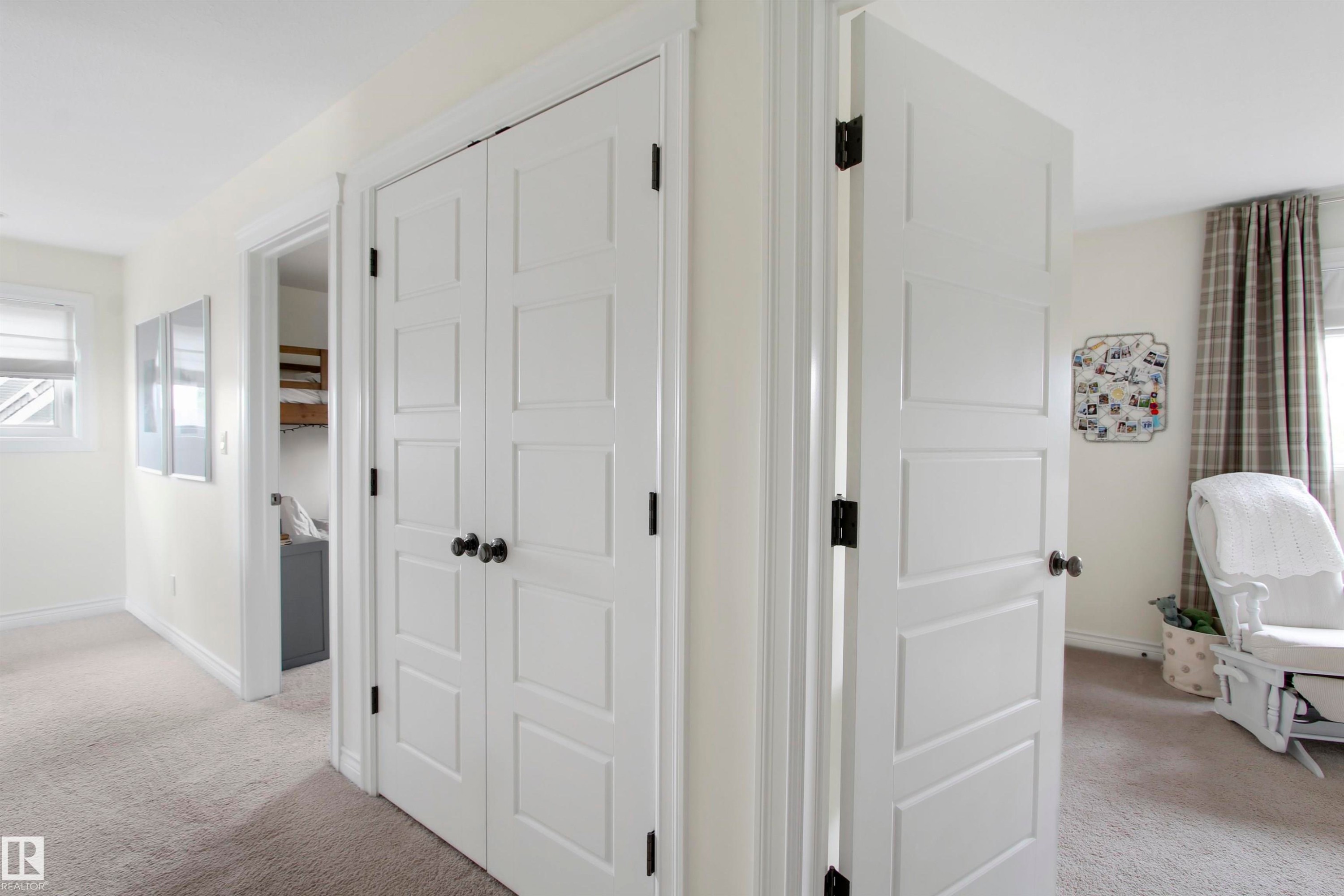 White paneled interior doors with black hardware, neutral wall paint, and gray carpeted flooring - 34 Falcon Road, Cold Lake, AB