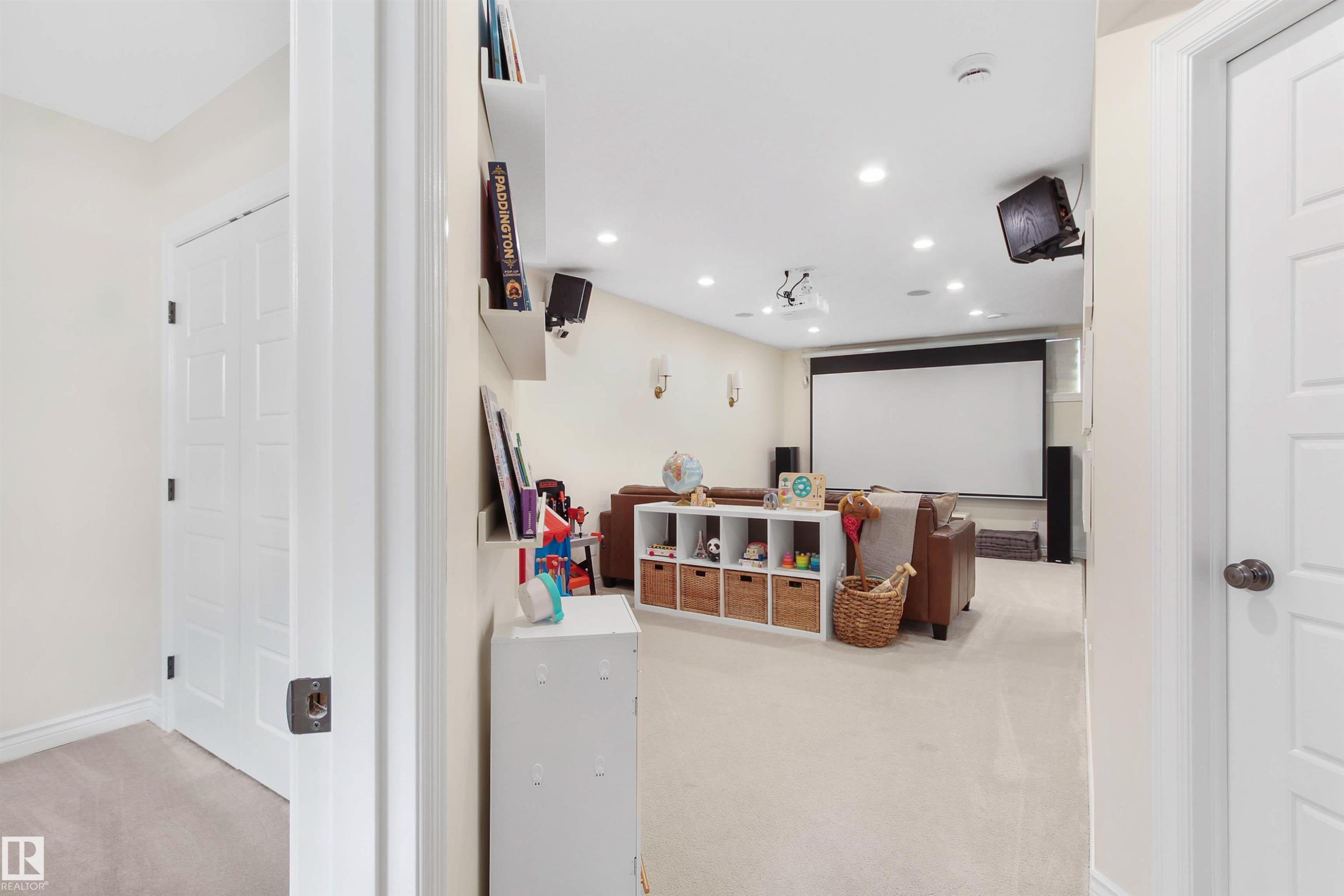 Spacious media room featuring a large projector screen, recessed lighting, wall-mounted speakers, and light-toned carpet flooring - 34 Falcon Road, Cold Lake, AB
