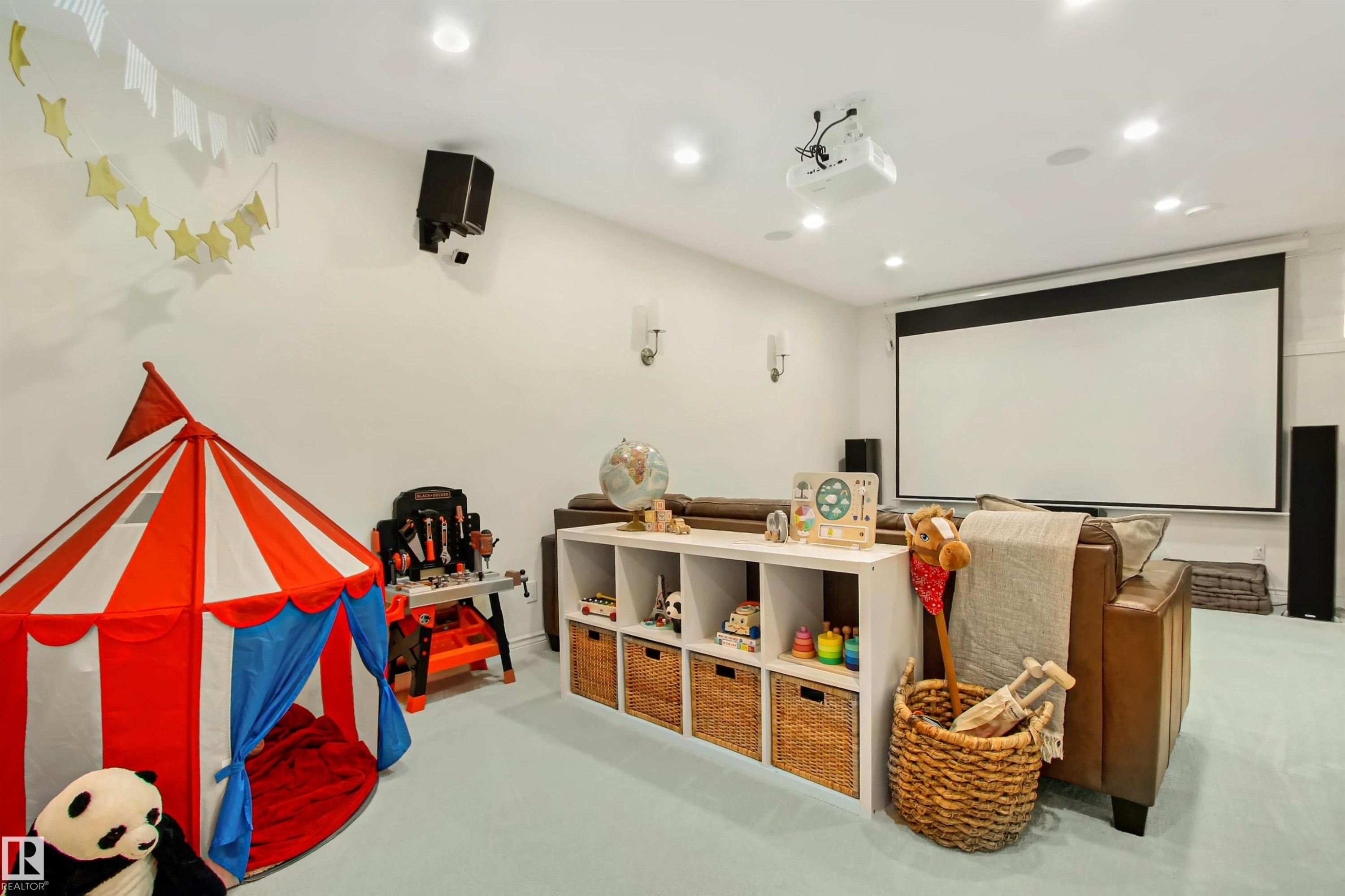 Entertainment room featuring a ceiling-mounted projector, large projection screen, recessed lighting, and wall-mounted speakers - 34 Falcon Road, Cold Lake, AB